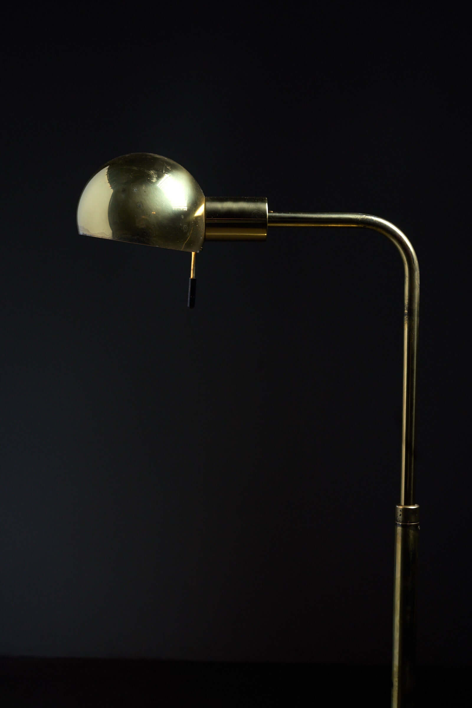 Metalarte floor lamp in polished brass, 1970s with a hemispherical shade against a dark background.