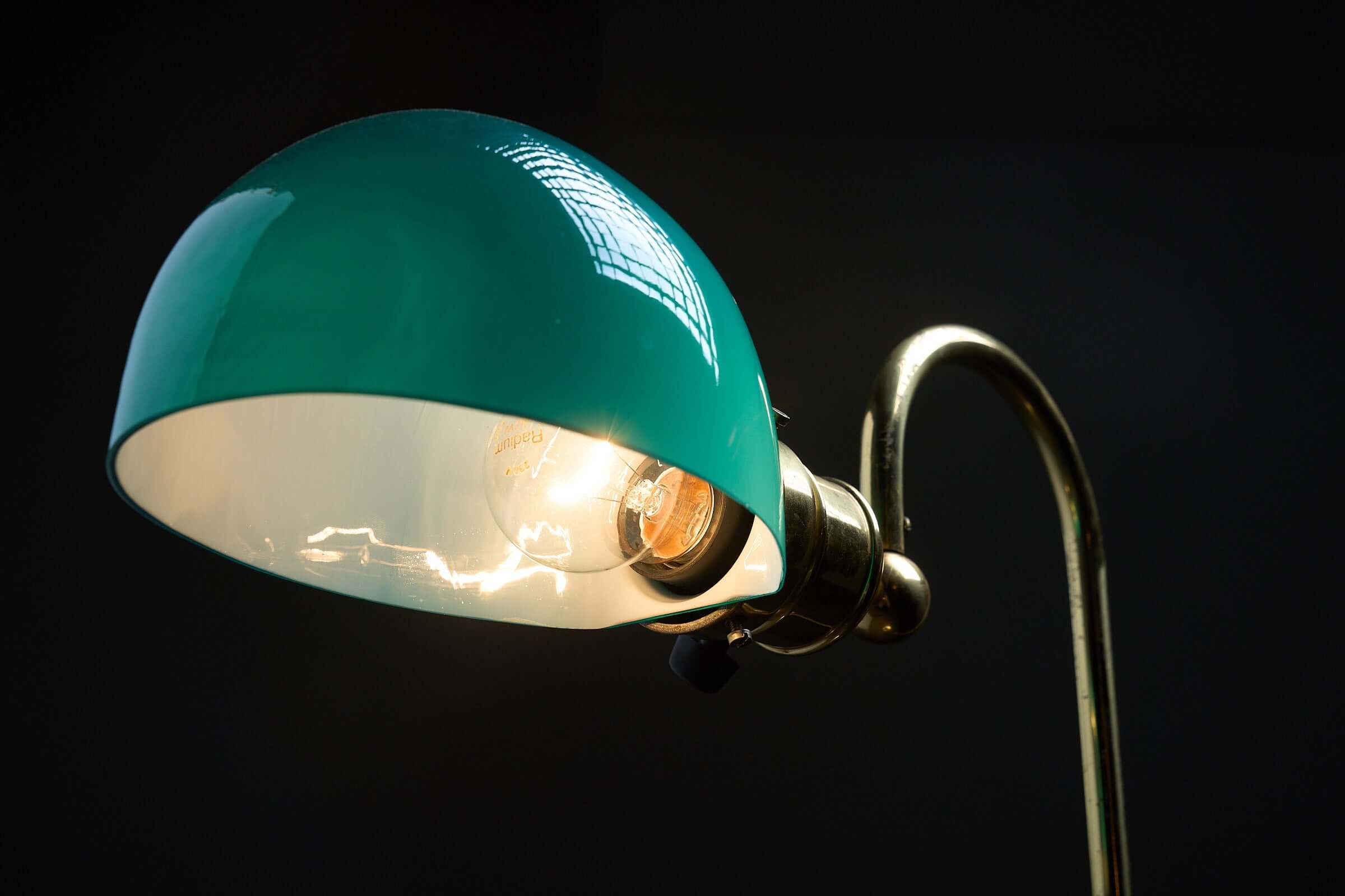 Floor lamp in brass with green glass shade, 1970s featuring a shiny green glass shade and curved brass arm.
