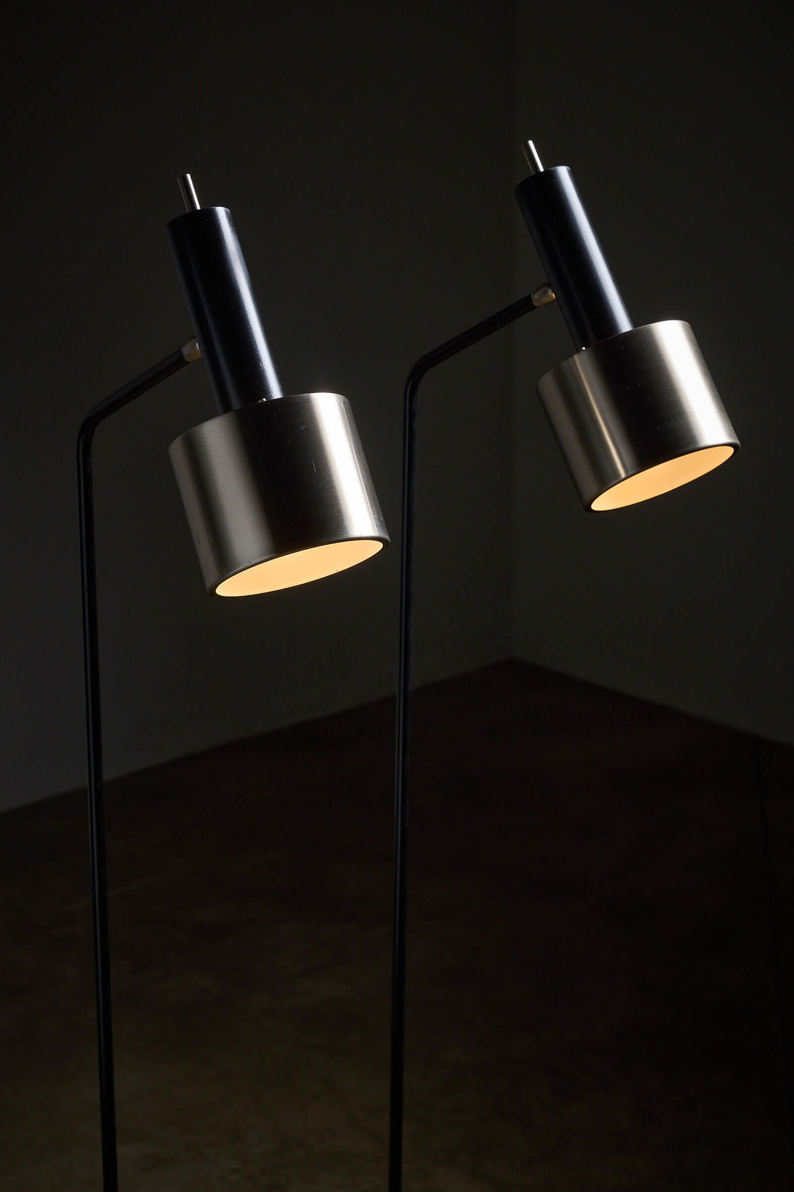 Pair of floor lamps in black metal with brushed aluminum shades, 1970s, featuring slender frames and minimalist design.