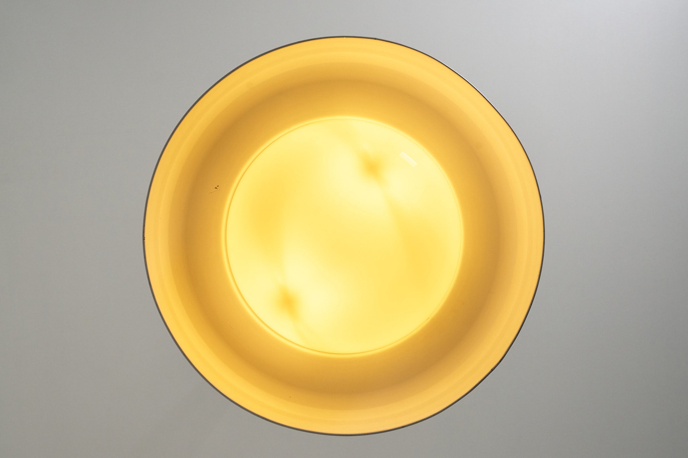 Large Brass and Yellow Glass Pendant casting a soft, warm yellow glow for ambient lighting.