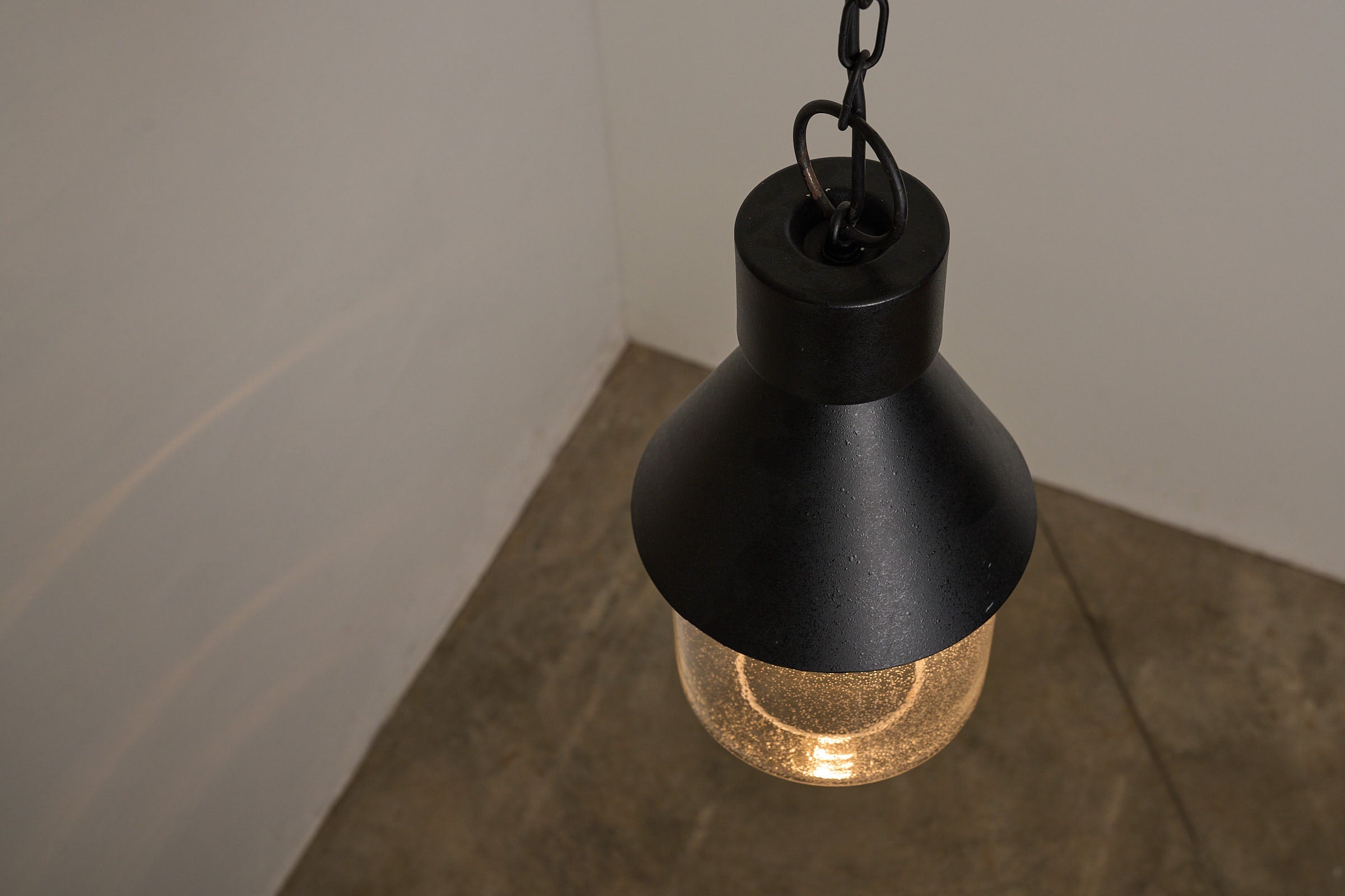 BOOM Ceiling Lamp, Black Metal & Bubble Glass Pendant hanging in a minimalist space with warm light.