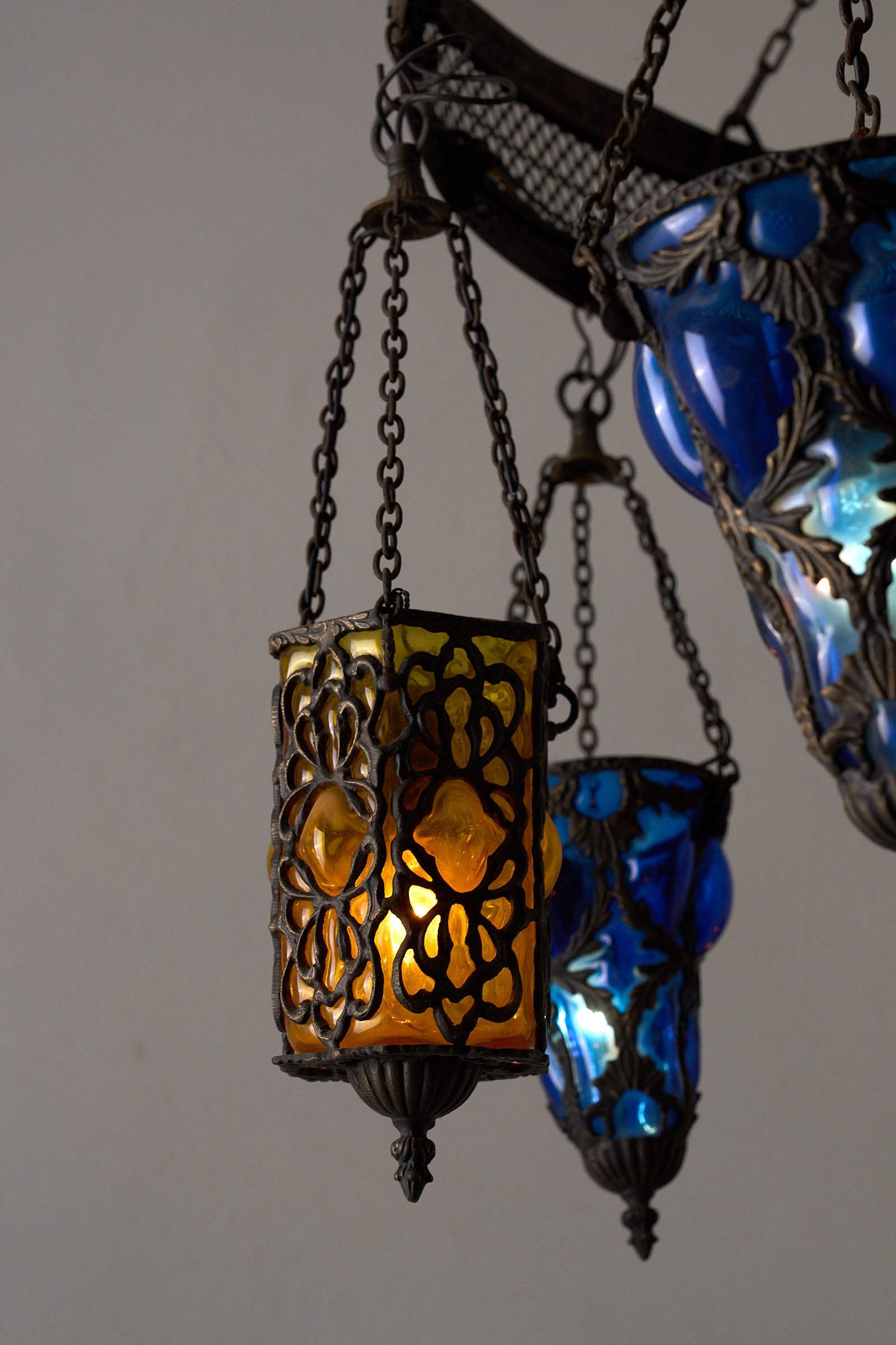 Moroccan Chandelier with Six Colored Glass Pendants featuring intricate brasswork and vivid amber and blue glass.