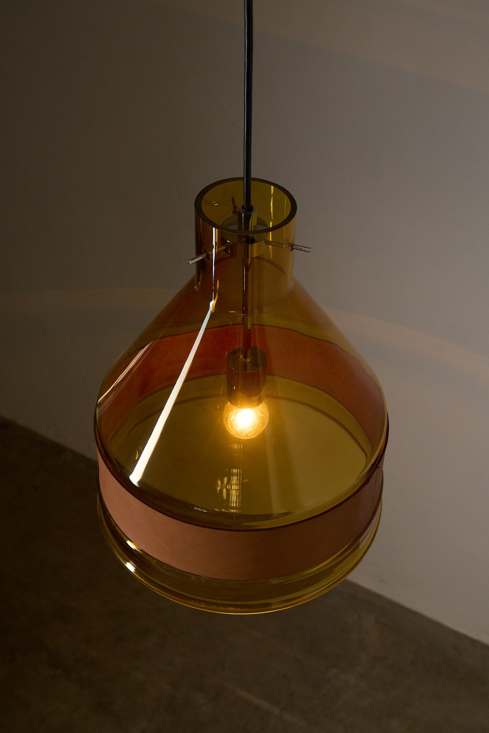 Amber Glass and Leather Pendant Lamp by J.T. Kalmar hanging with a warm light, showcasing its unique design from the 1970s.