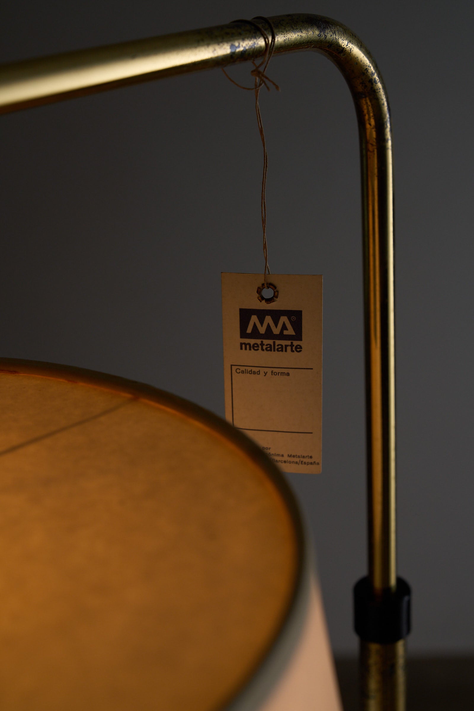 Close-up of Metalarte Spain adjustable floor lamp showing brass stem and attached label.