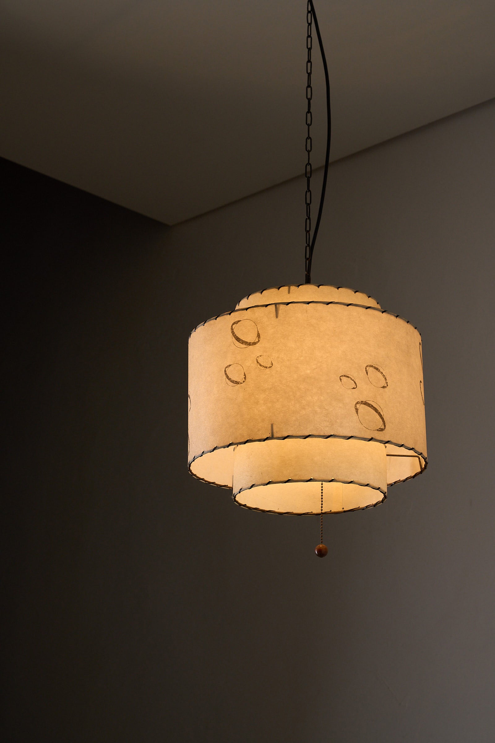 Parchment Pendant Lamp by Archaic Smile Inc, showcasing a double-tier design with a planet motif and hand-laced edges.