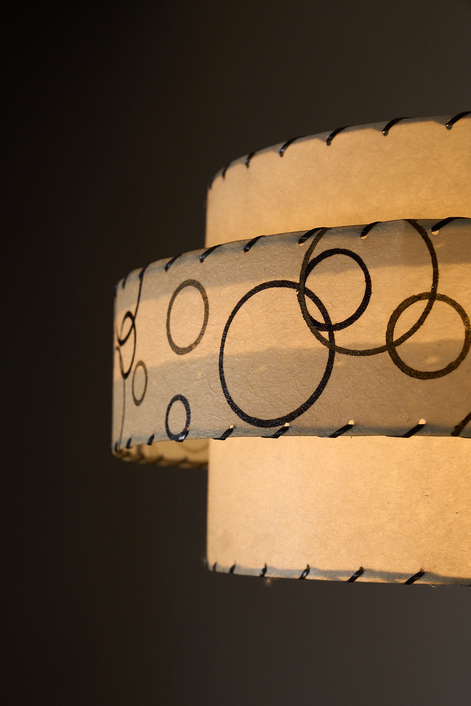Bubble Motif Pendant Lamp by Archaic Smile Inc. features a double-tiered parchment shade with bubble pattern.