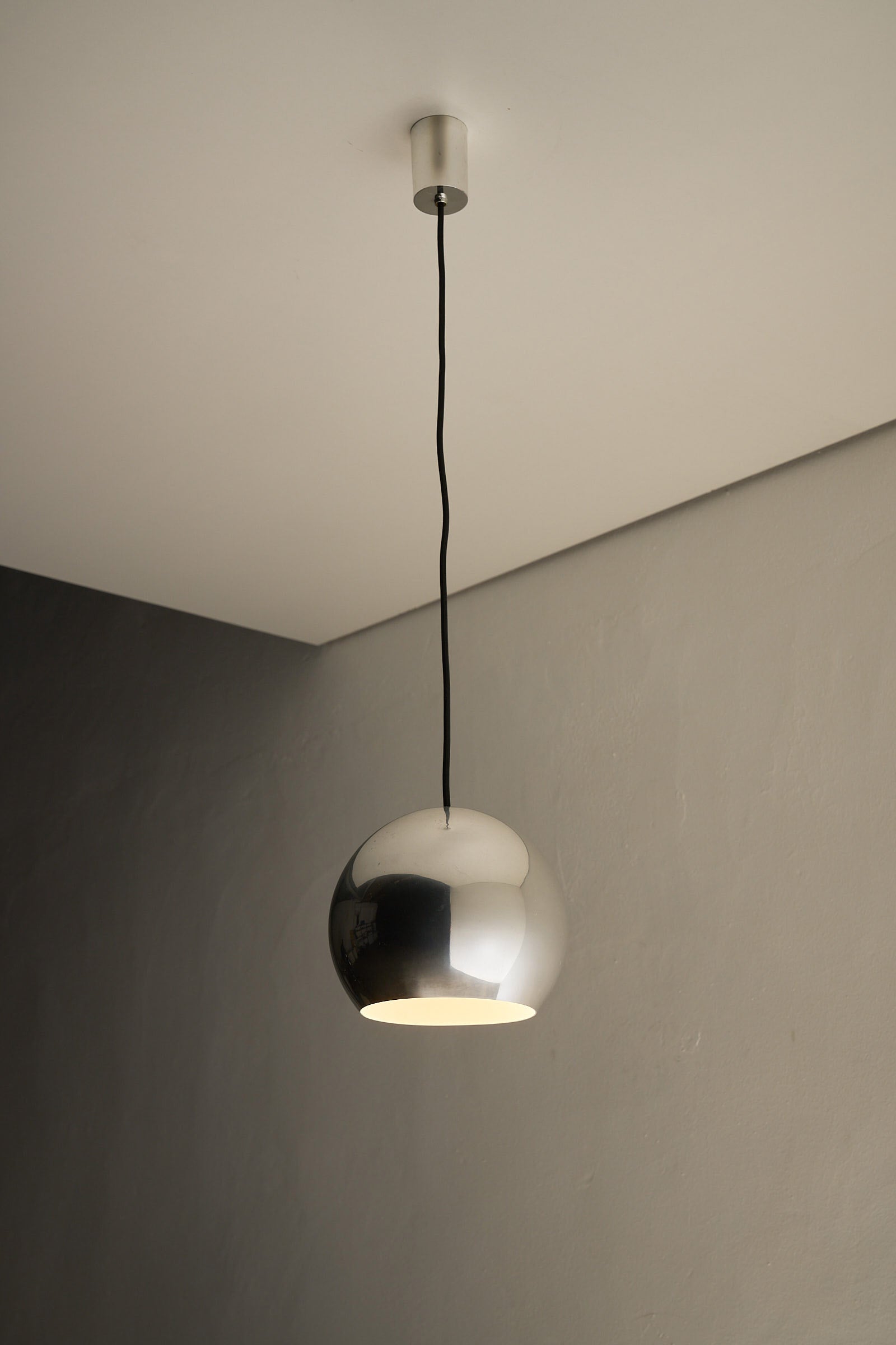 Chrome Sphere Pendant hanging from the ceiling, showcasing its sleek design and mid-century elegance.