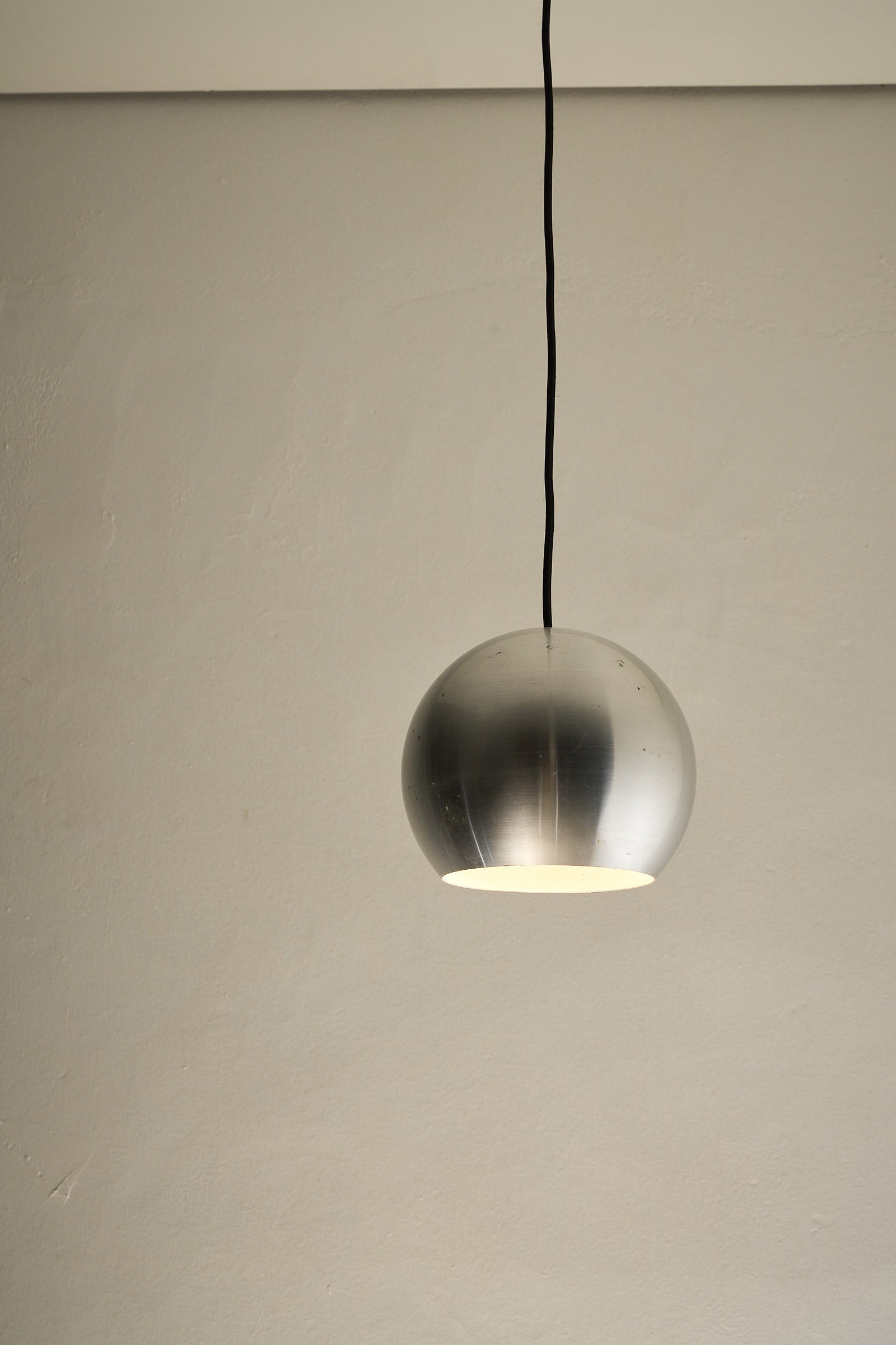 Brushed Aluminium Sphere Pendant hanging from a ceiling with a minimalist design, showcasing mid-century elegance.