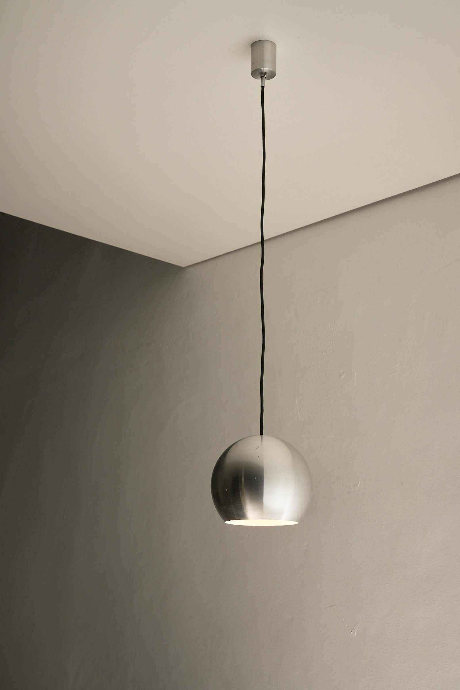 Brushed Aluminium Sphere Pendant hanging from a ceiling, showcasing sleek and modern design, ideal for contemporary spaces.