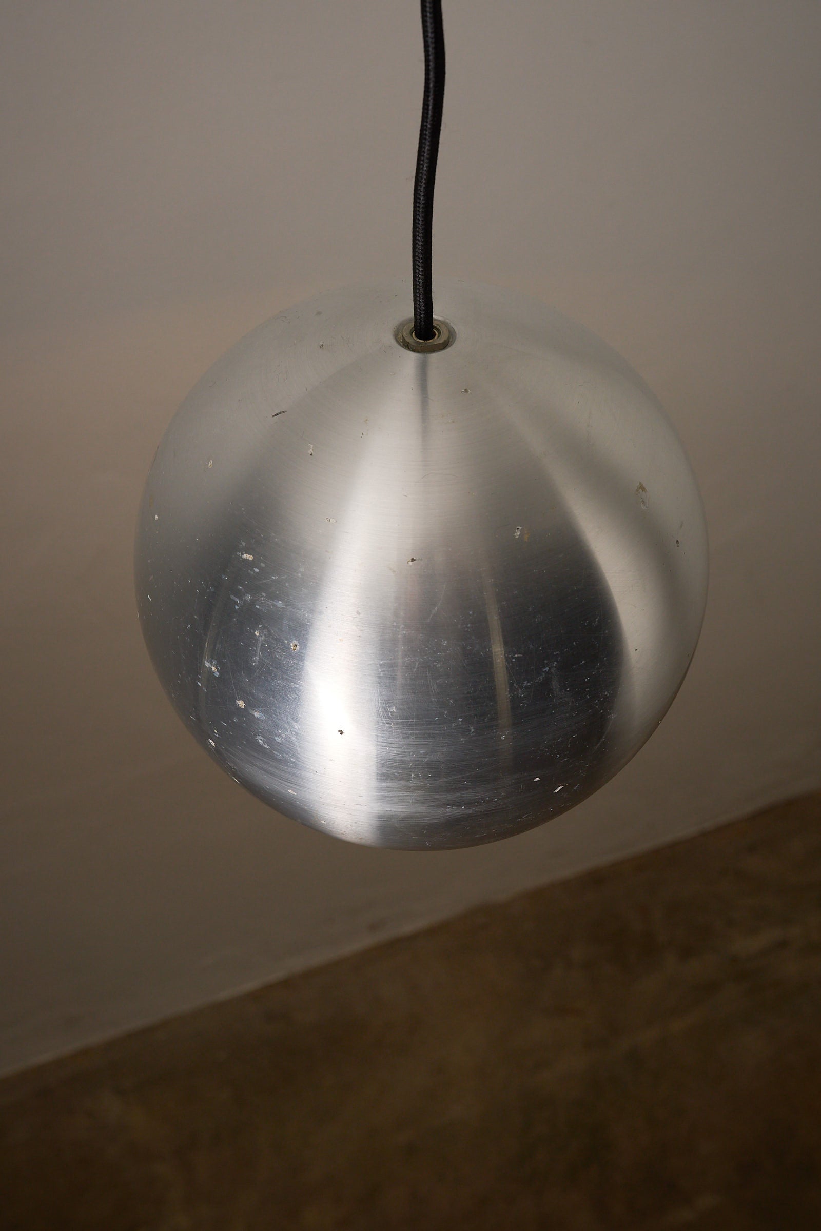 Brushed Aluminium Sphere Pendant hanging from the ceiling, showcasing mid-century German design.