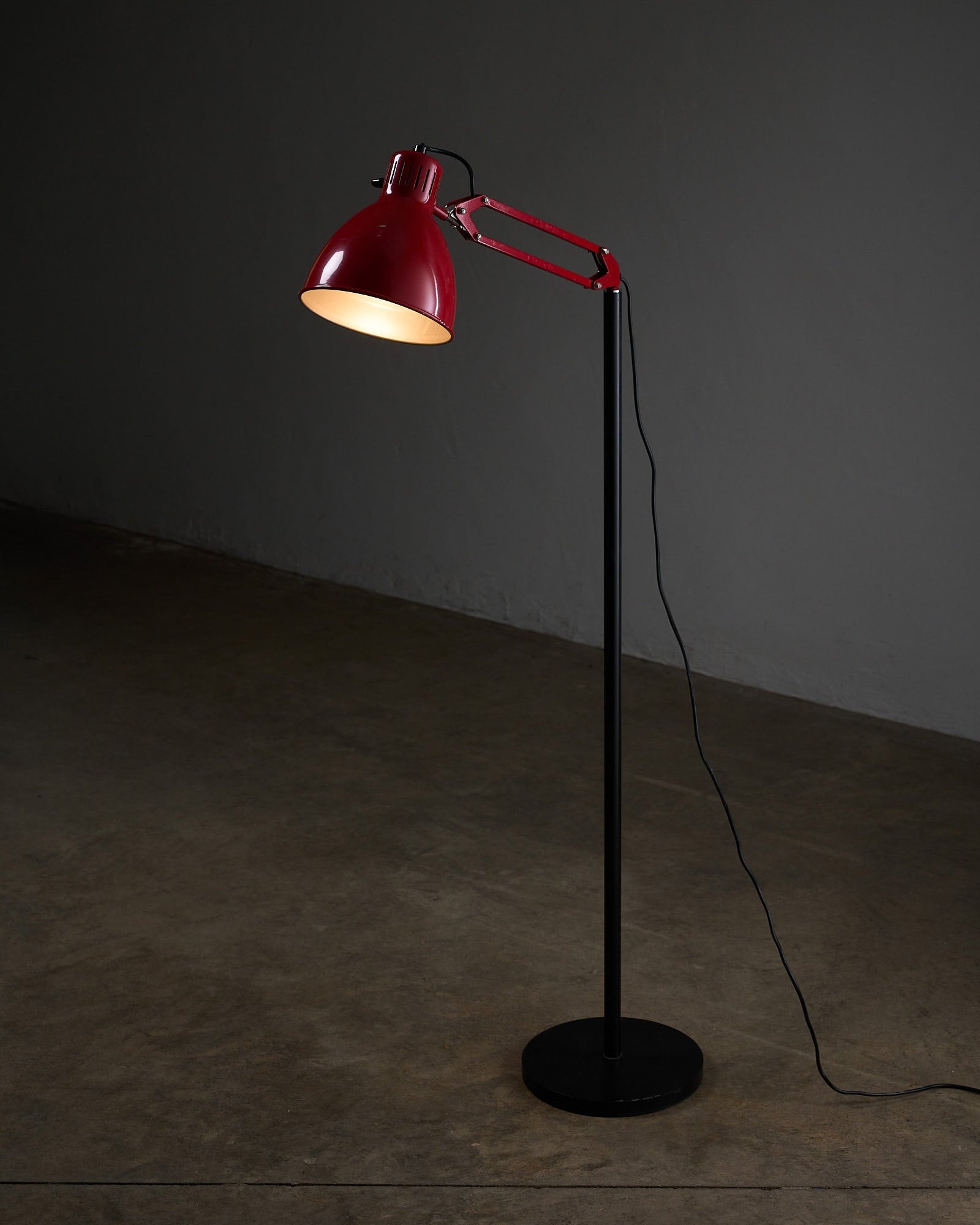 Metalarte “Arma” Adjustable Floor Lamp in Red and Black Enamel, 1970s illuminated in a stylish setting.