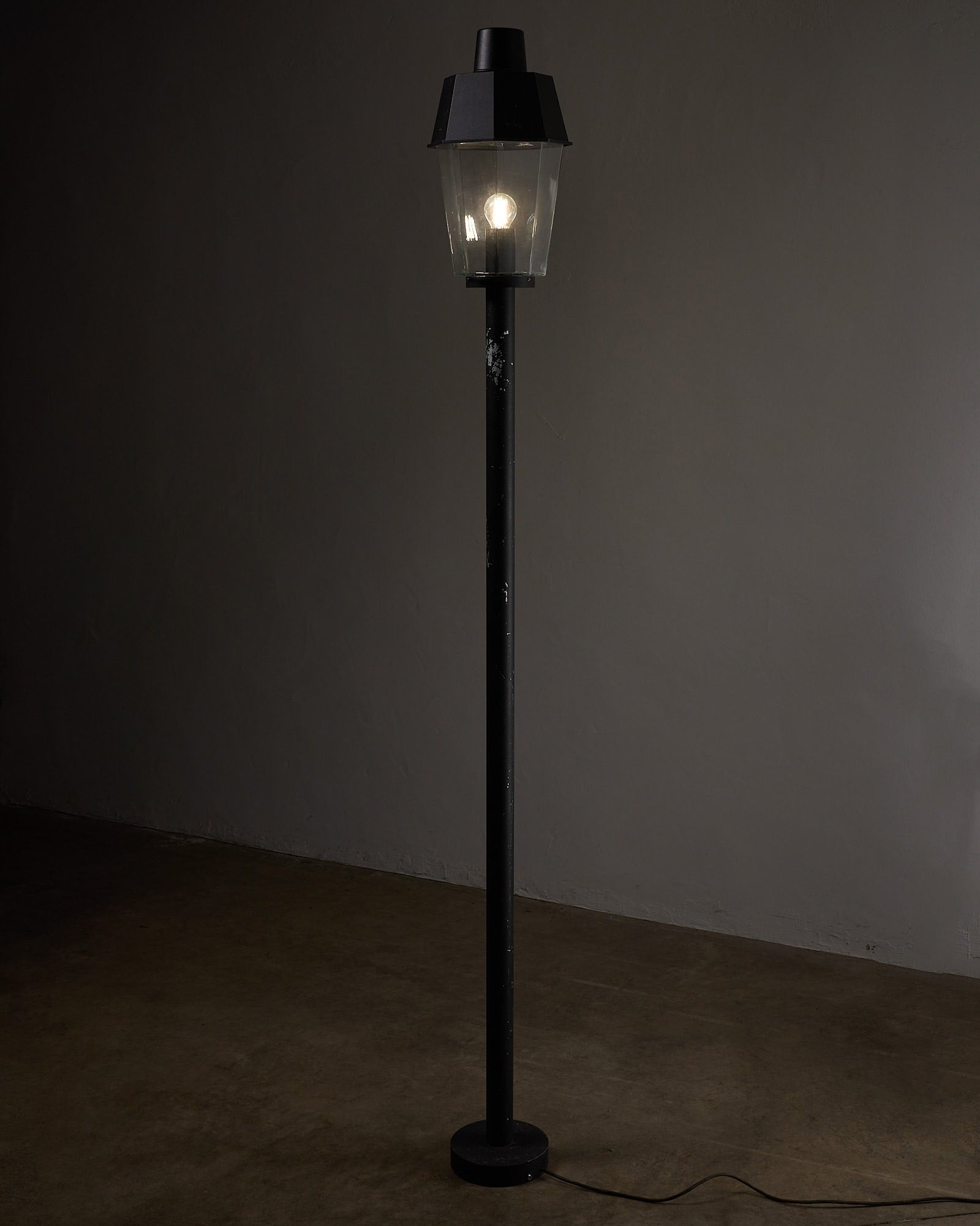 Outdoor Pole Lantern from Boom Bega standing on a circular base with clear glass shade and black metal pole.