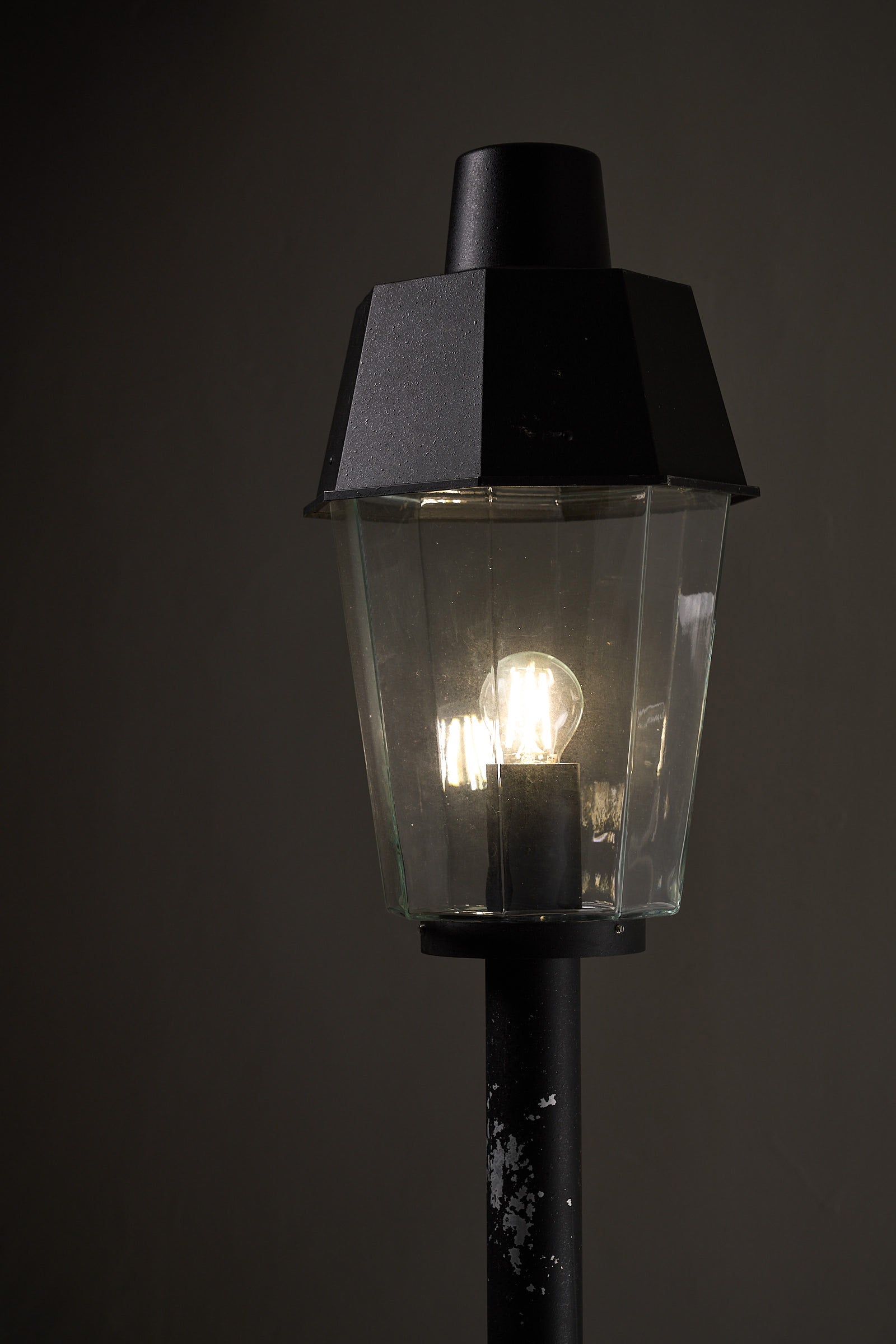 Close-up of the Outdoor Pole Lantern from Boom Bega showcasing the clear glass shade and black metal pole.