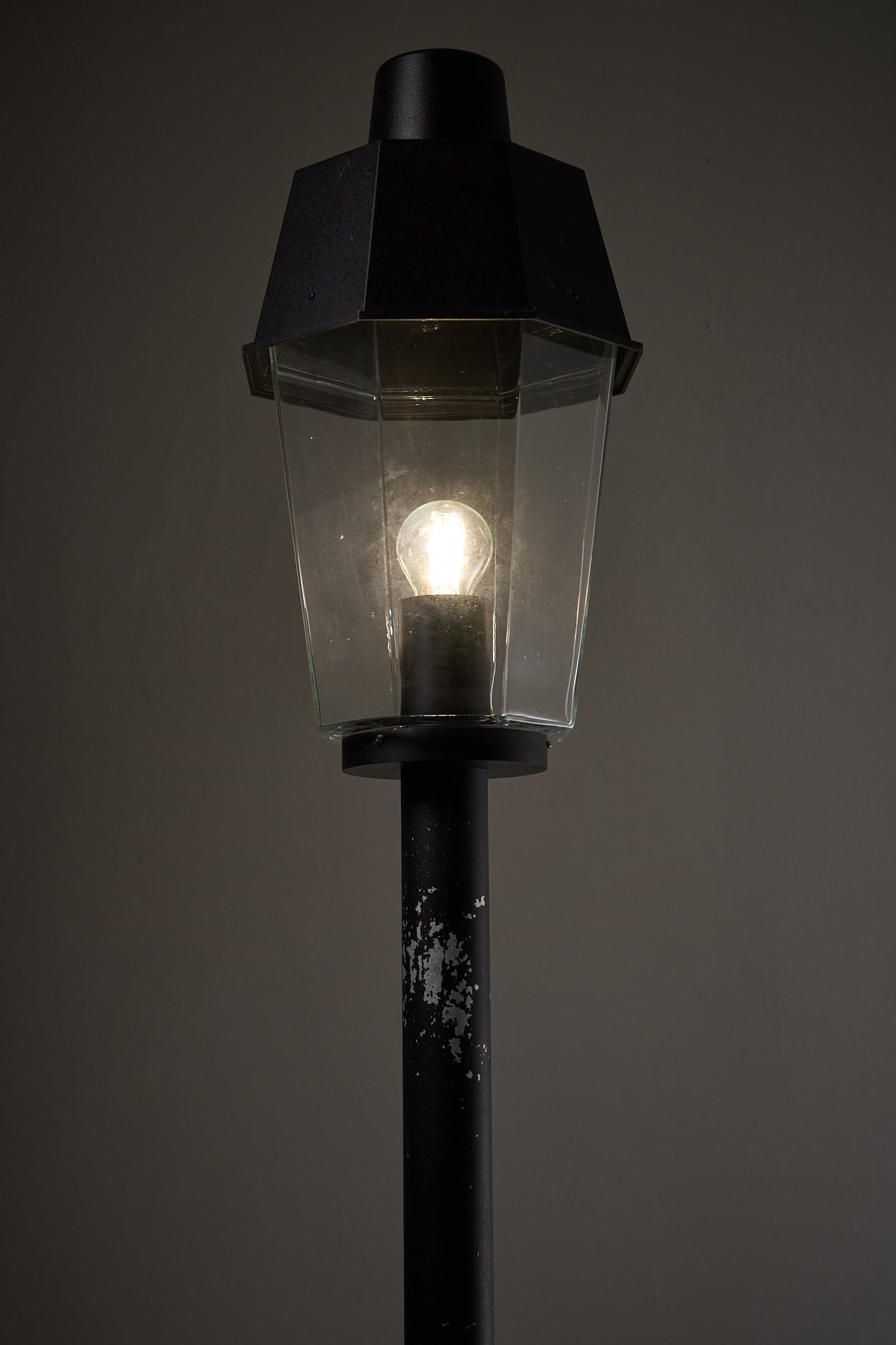Outdoor Pole Lantern from Boom Bega with a clear glass shade and black metal pole, perfect for outdoor lighting.