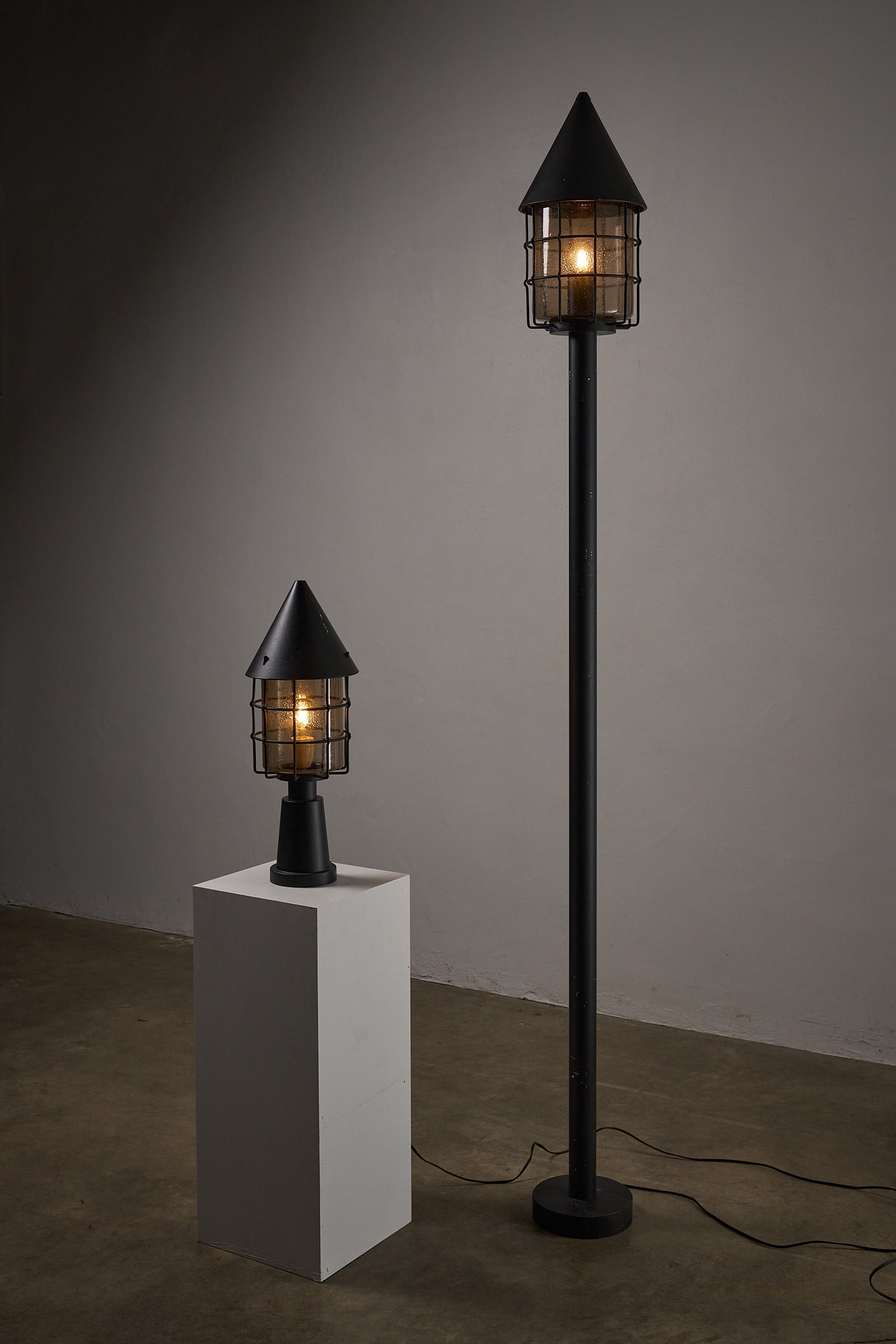 Tall Outdoor Lantern by Boom BEGA displayed in modern setting with a tall conical design and protective glass enclosure.