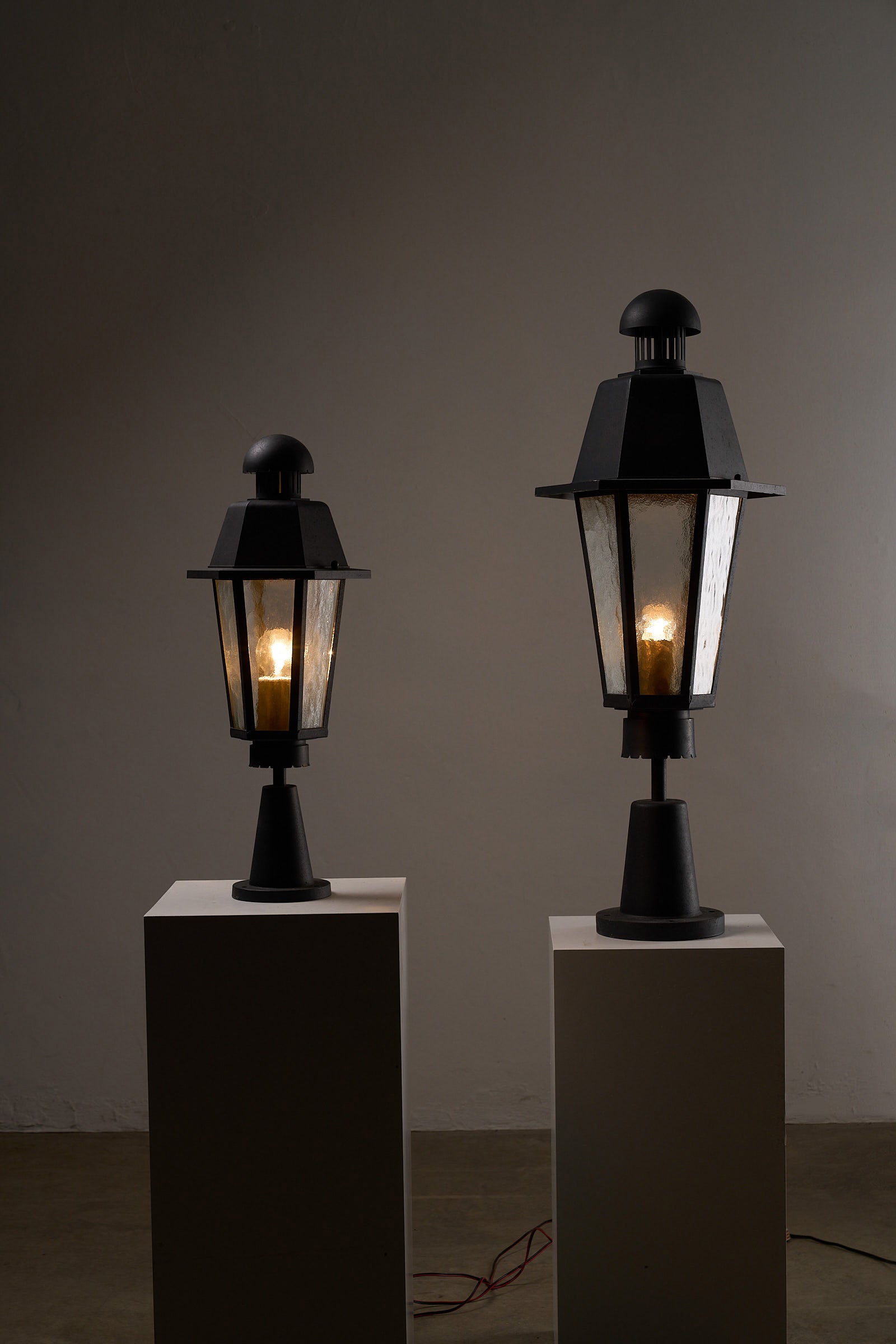 Boom BEGA Outdoor Lantern Medium displayed on pedestals, showcasing durable cast metal and textured glass design.