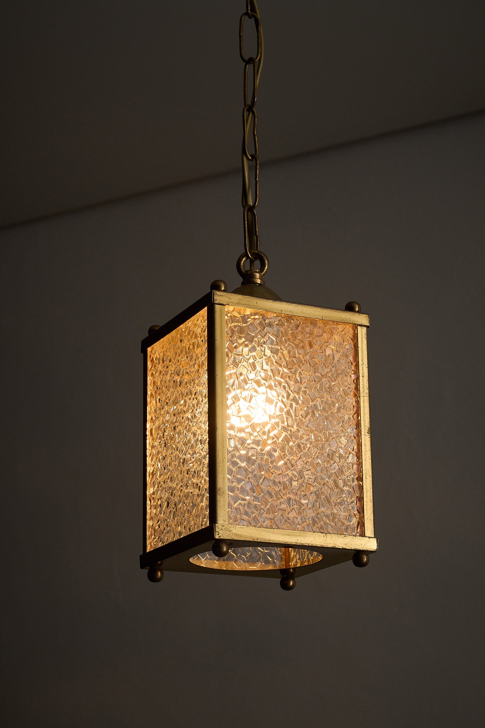 Mid-Century Brass Pendant Lamp with Textured Glass Shade illuminating a warm ambiance.