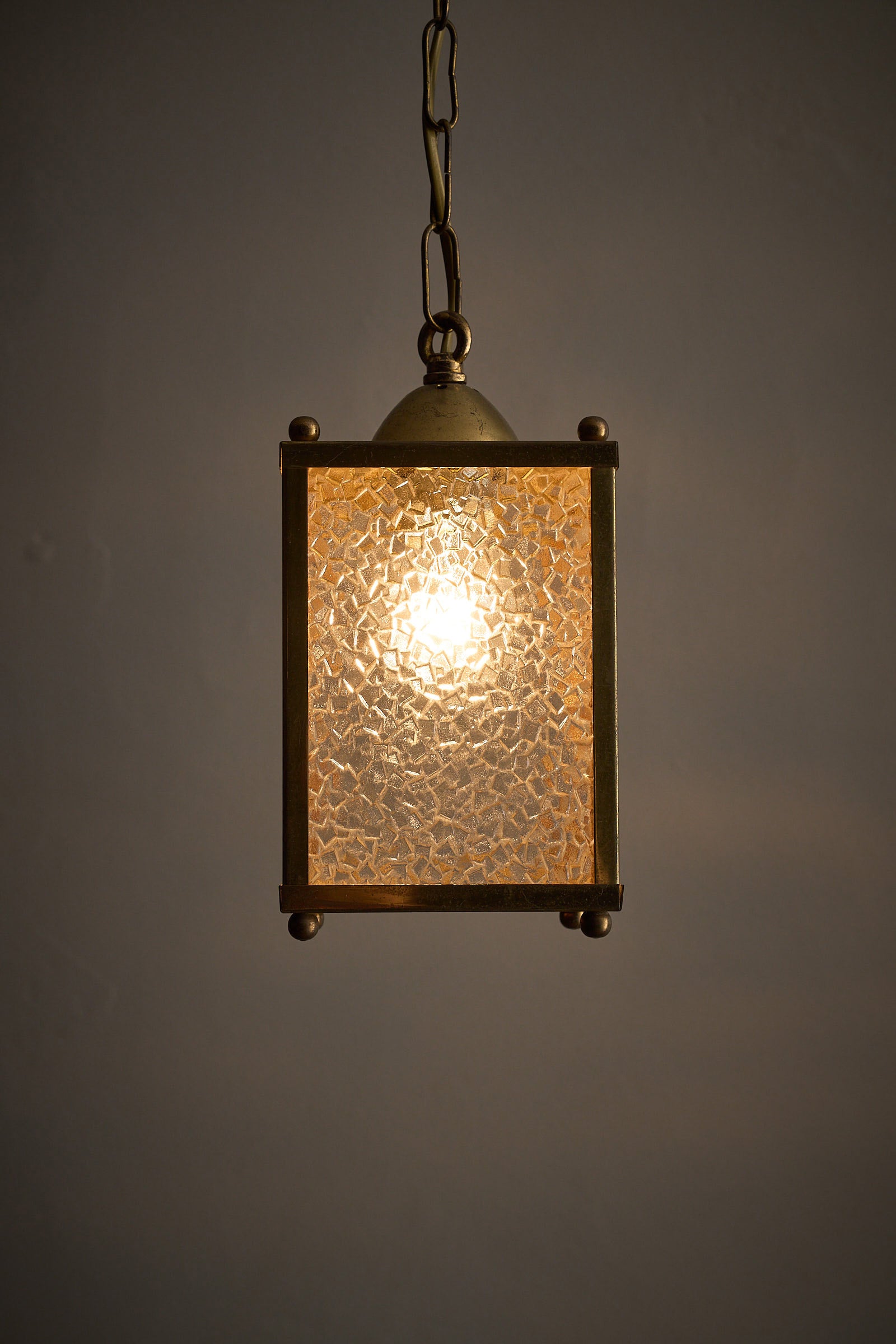 Mid-Century Brass Pendant Lamp with Textured Glass Shade illuminating a warm ambient light.