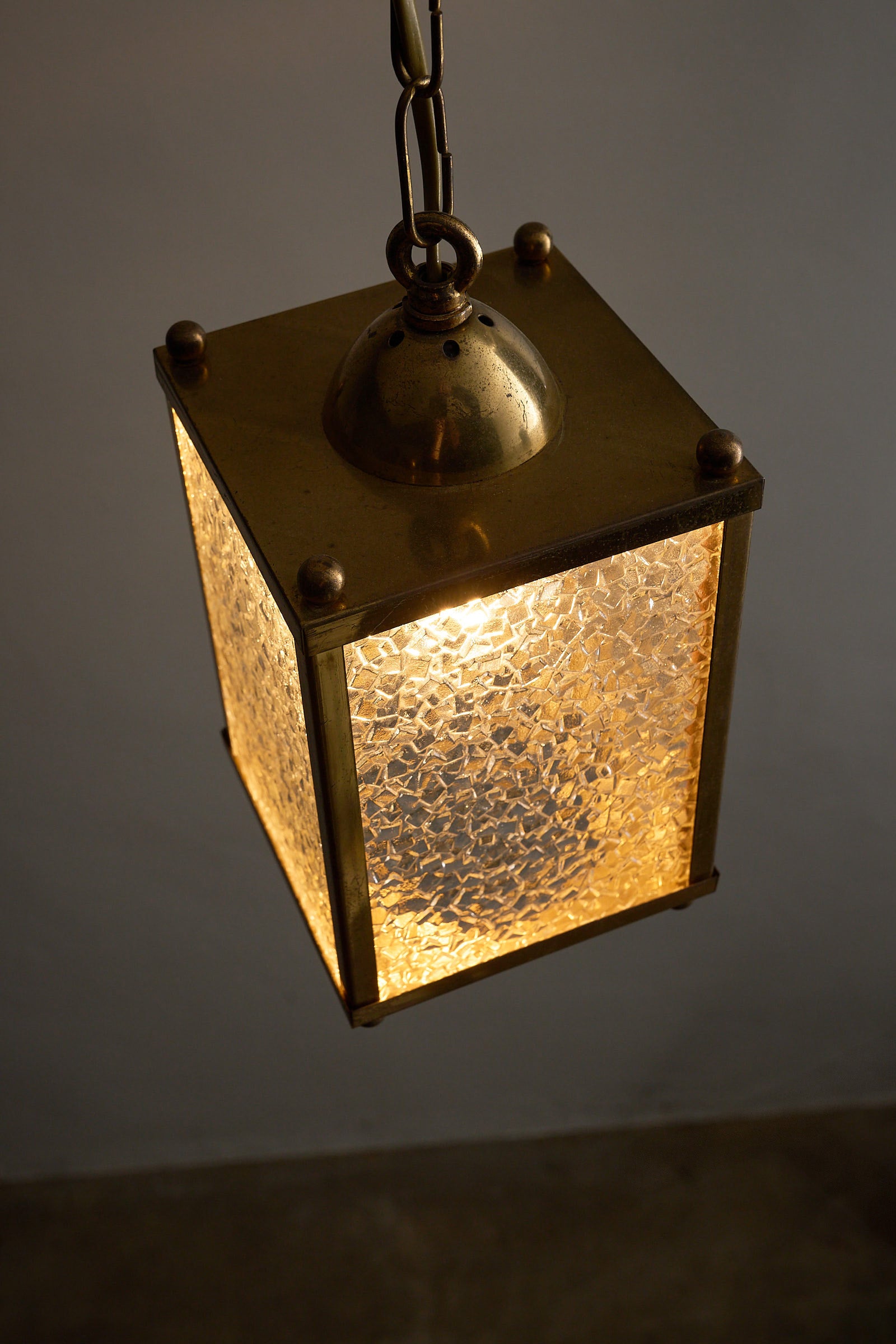 Mid-Century Brass Pendant Lamp with Textured Glass Shade illuminating a warm ambient light.