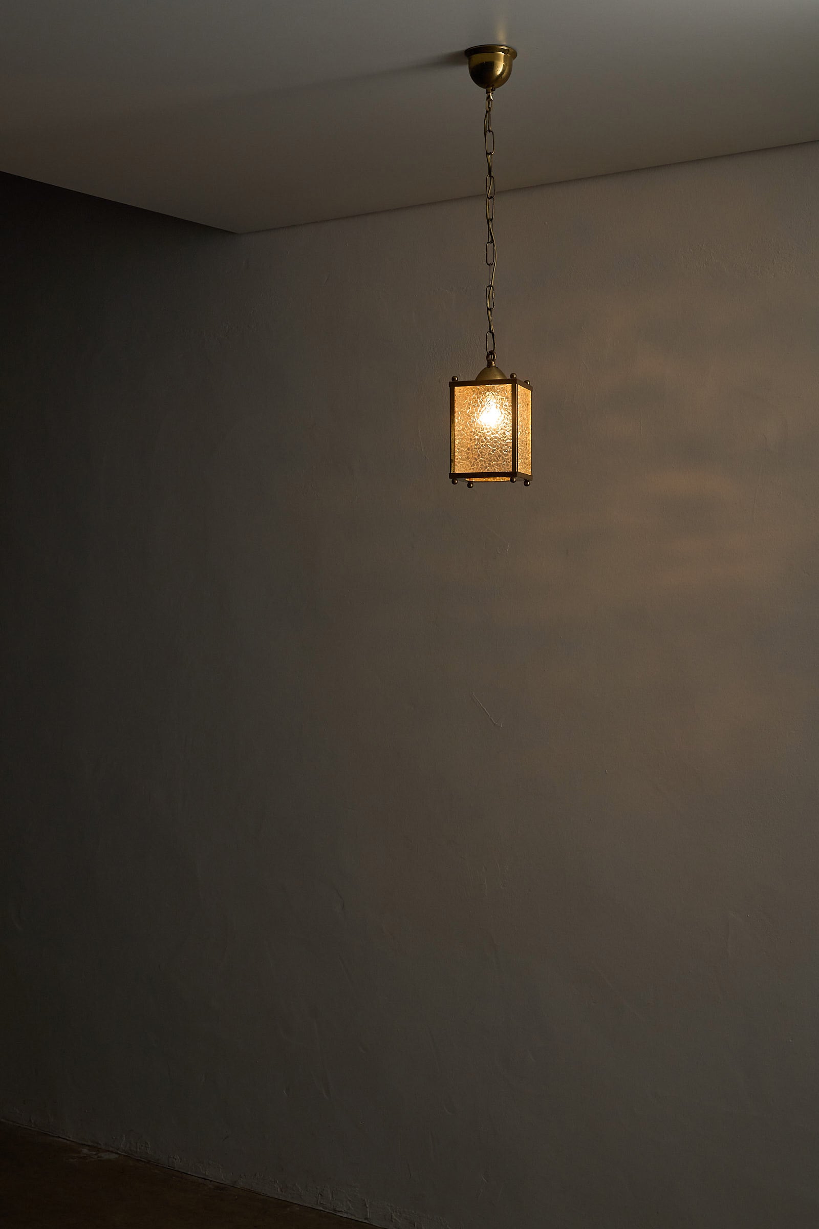 Mid-Century Brass Pendant Lamp with Textured Glass Shade illuminating a wall.