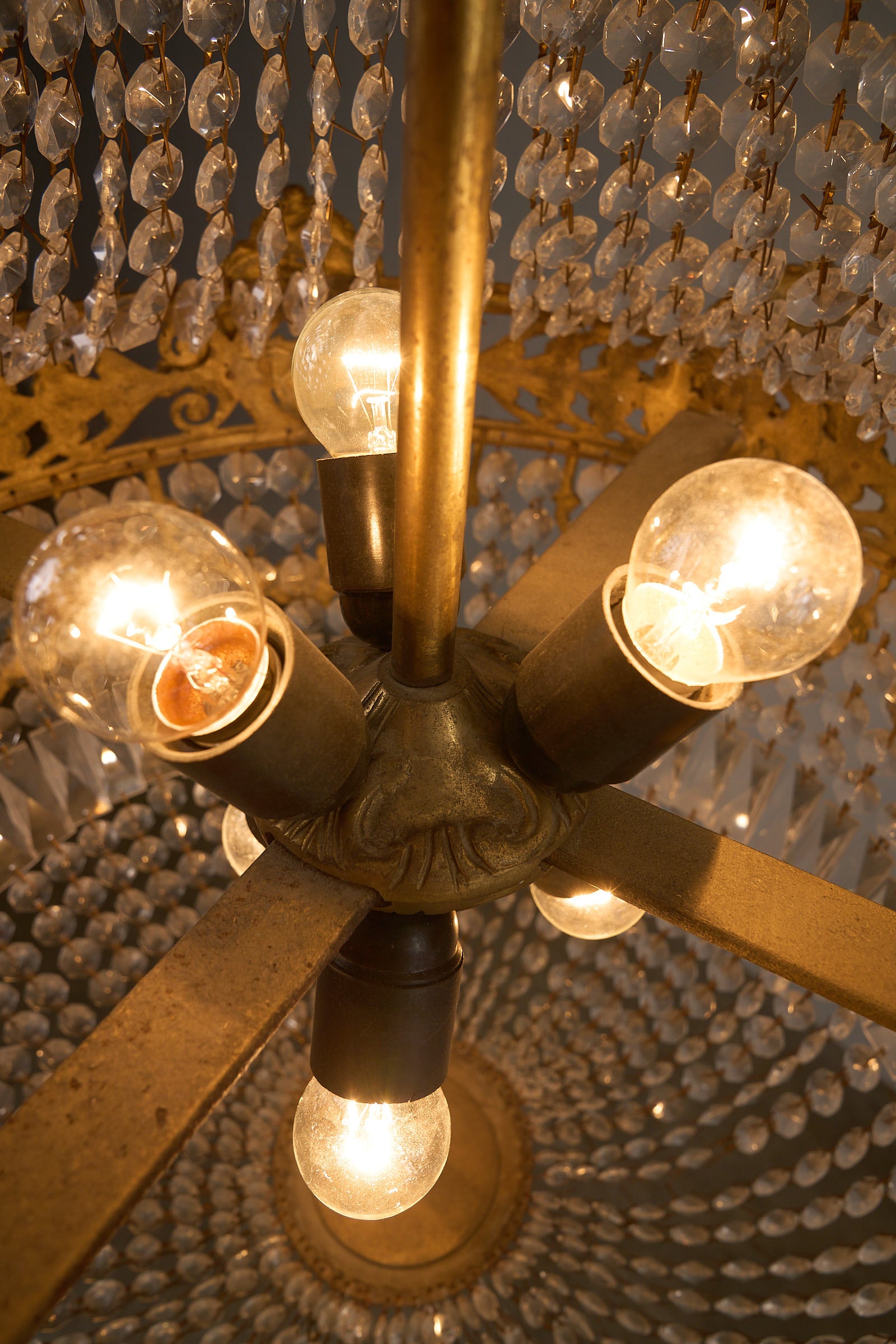 Medium Empire-Style Brass and Crystal Chandelier with Garland Detailing, 20th Century, showing interior bulbs and crystal details.