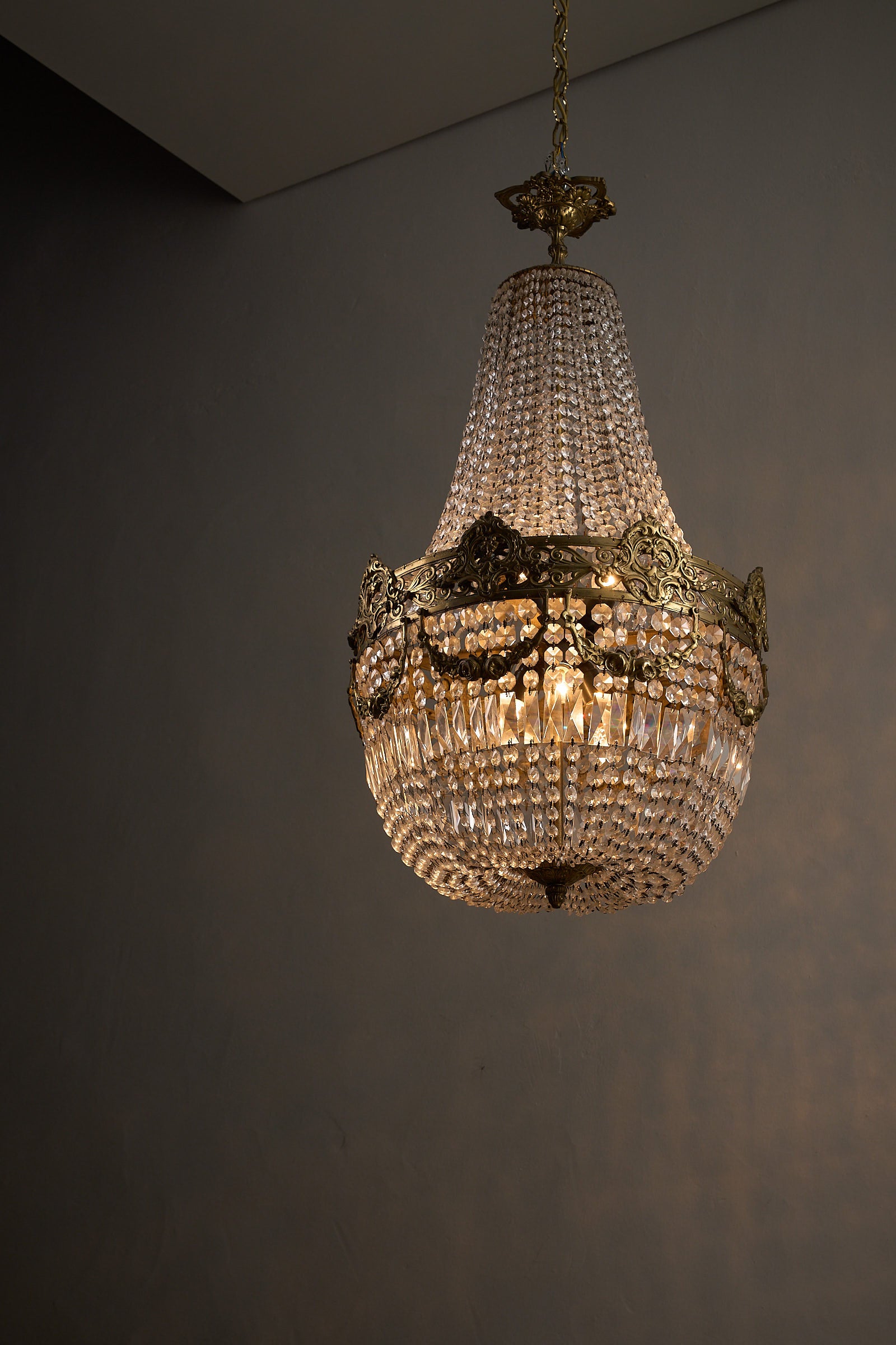Medium Empire-Style Brass and Crystal Chandelier with Garland Detailing, 20th Century hanging elegantly.