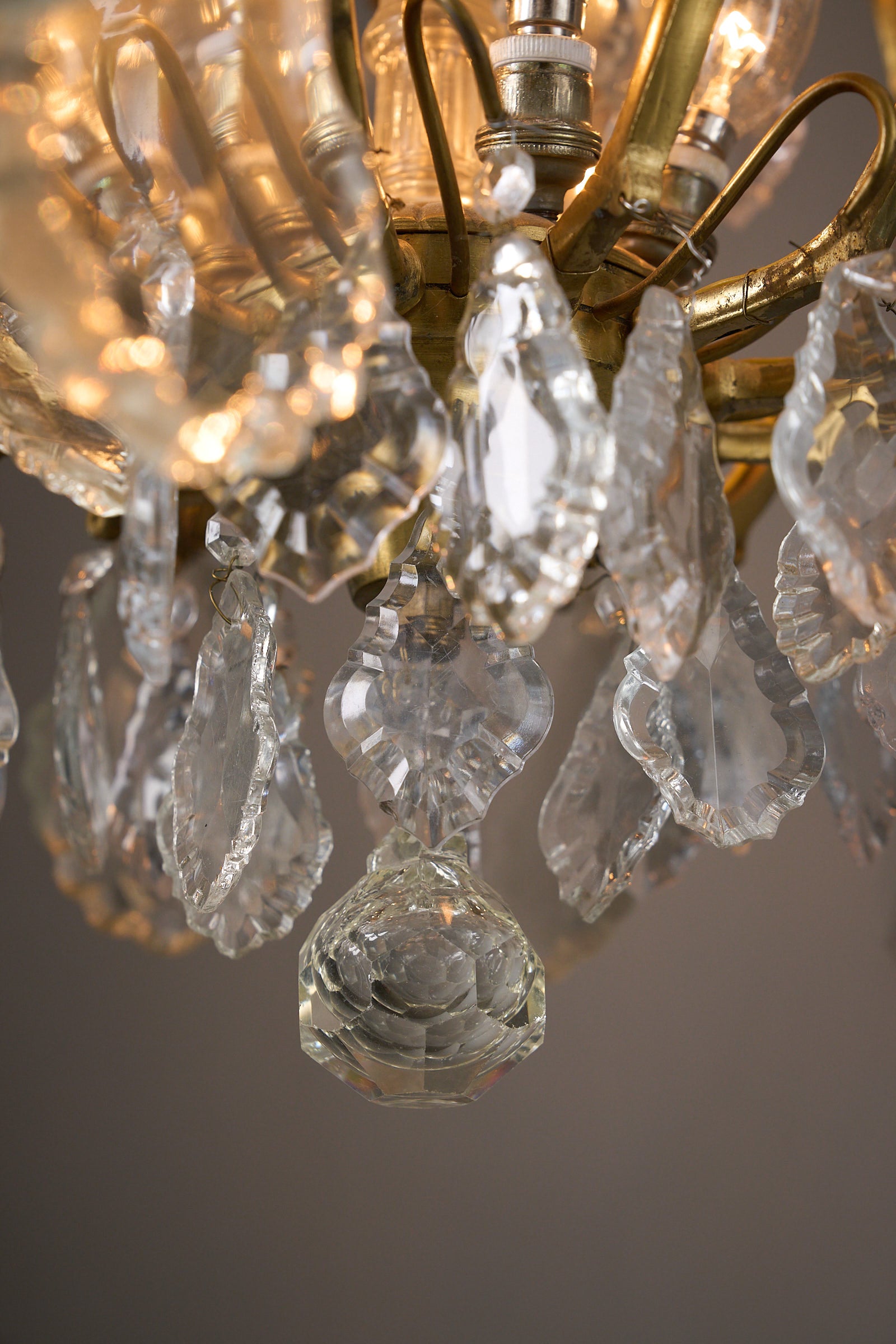 Close-up of the Empire-Style Chandelier in Brass and Crystal featuring cut crystal pendants and ornate brass arms.