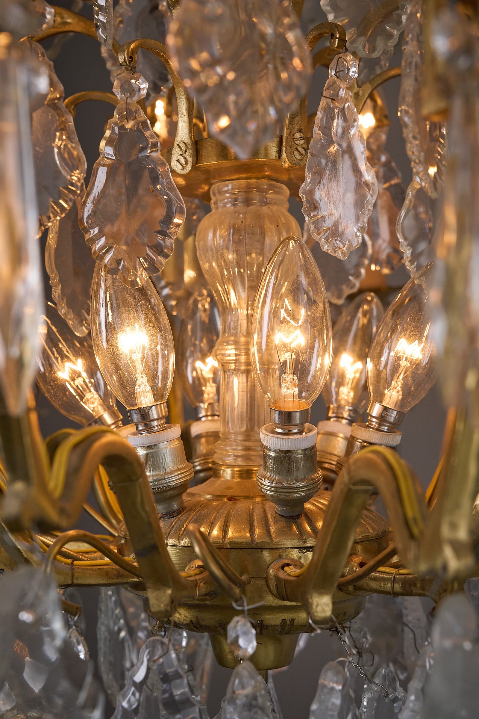 Empire-Style Chandelier in Brass and Crystal with glowing candle-style lights and cut crystal embellishments.