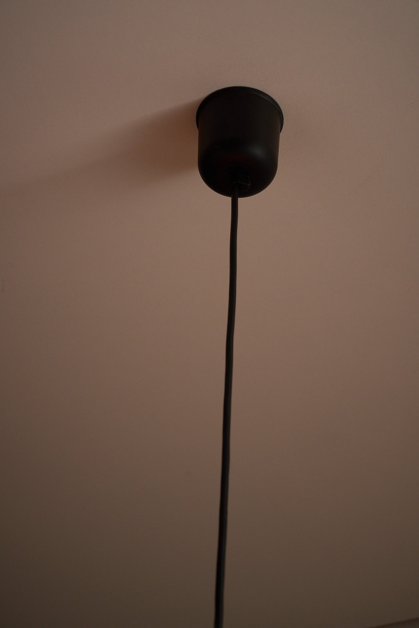 Ceiling Lamp with Double Acrylic Shade in Orange and White hanging from a black cord and socket against a light ceiling.