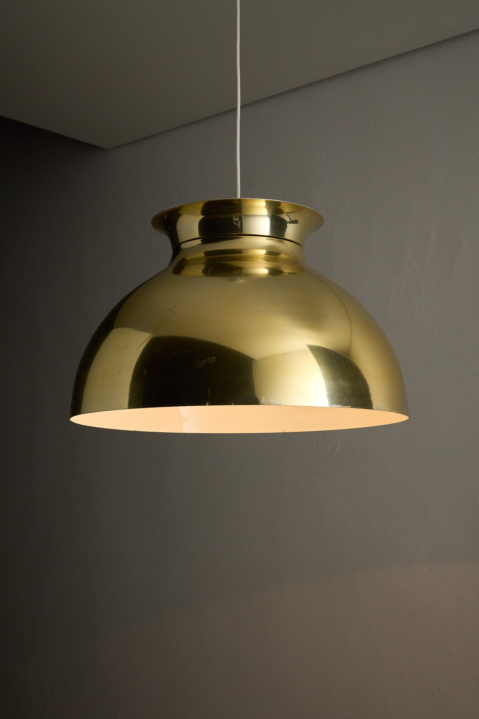 Large Brass Dome Pendant featuring a polished brass shade and white interior, suspended from a sleek white cable.