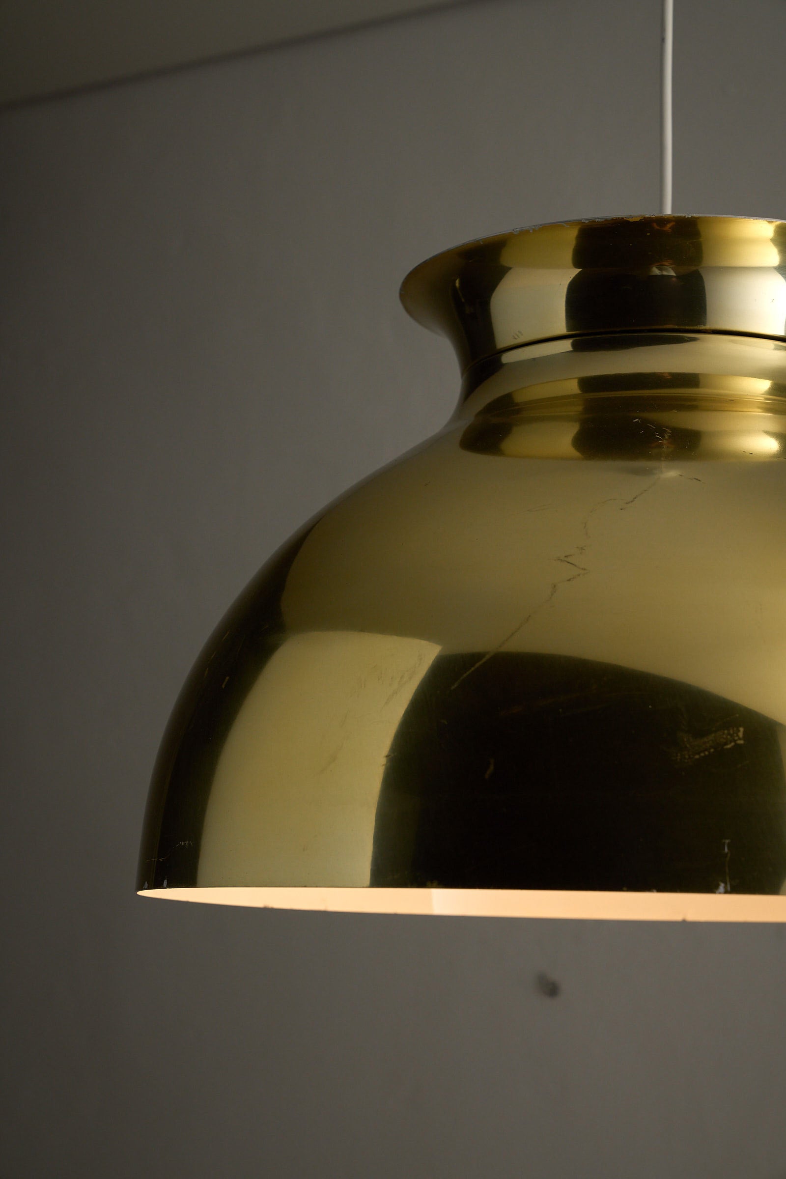 Large Brass Dome Pendant with polished shade and white interior, highlighting visible age-related wear.