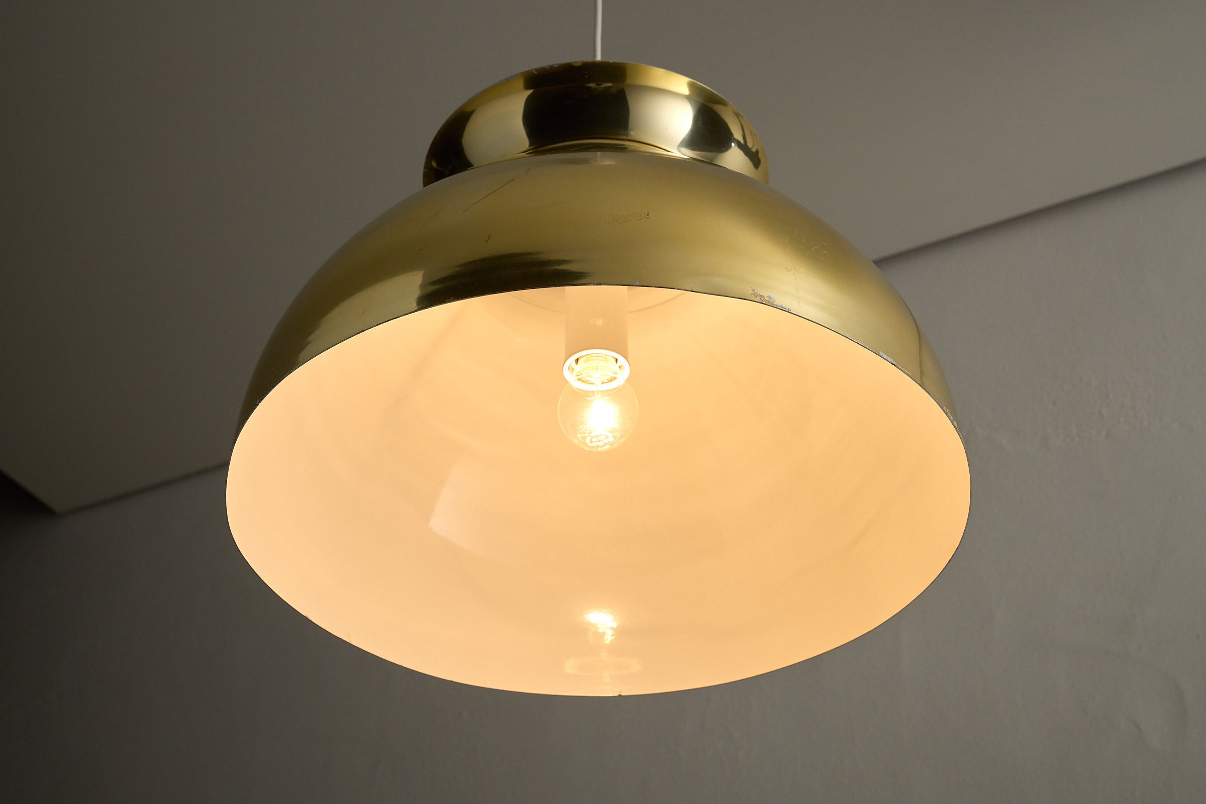 Large Brass Dome Pendant with polished brass shade and white interior, providing warm downlight.