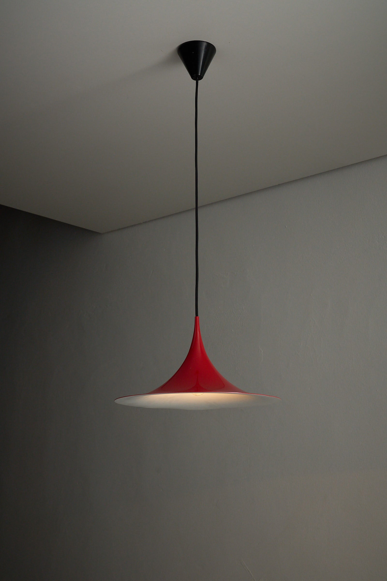 Fog&Mørup Red Semi Pendant Lamp hanging from ceiling, showcasing its elegant design with red exterior and white interior.