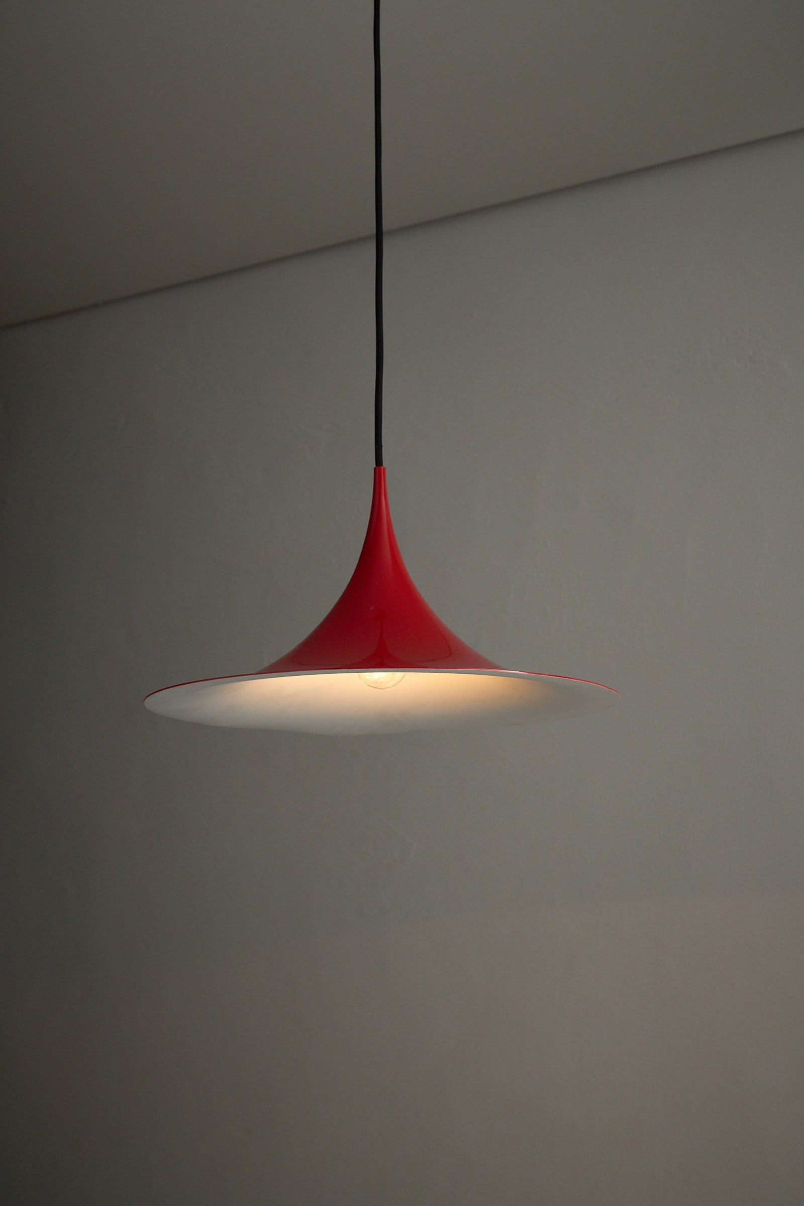 Fog&Mørup Red Semi Pendant Lamp hanging against a neutral wall, showcasing its red and white design.