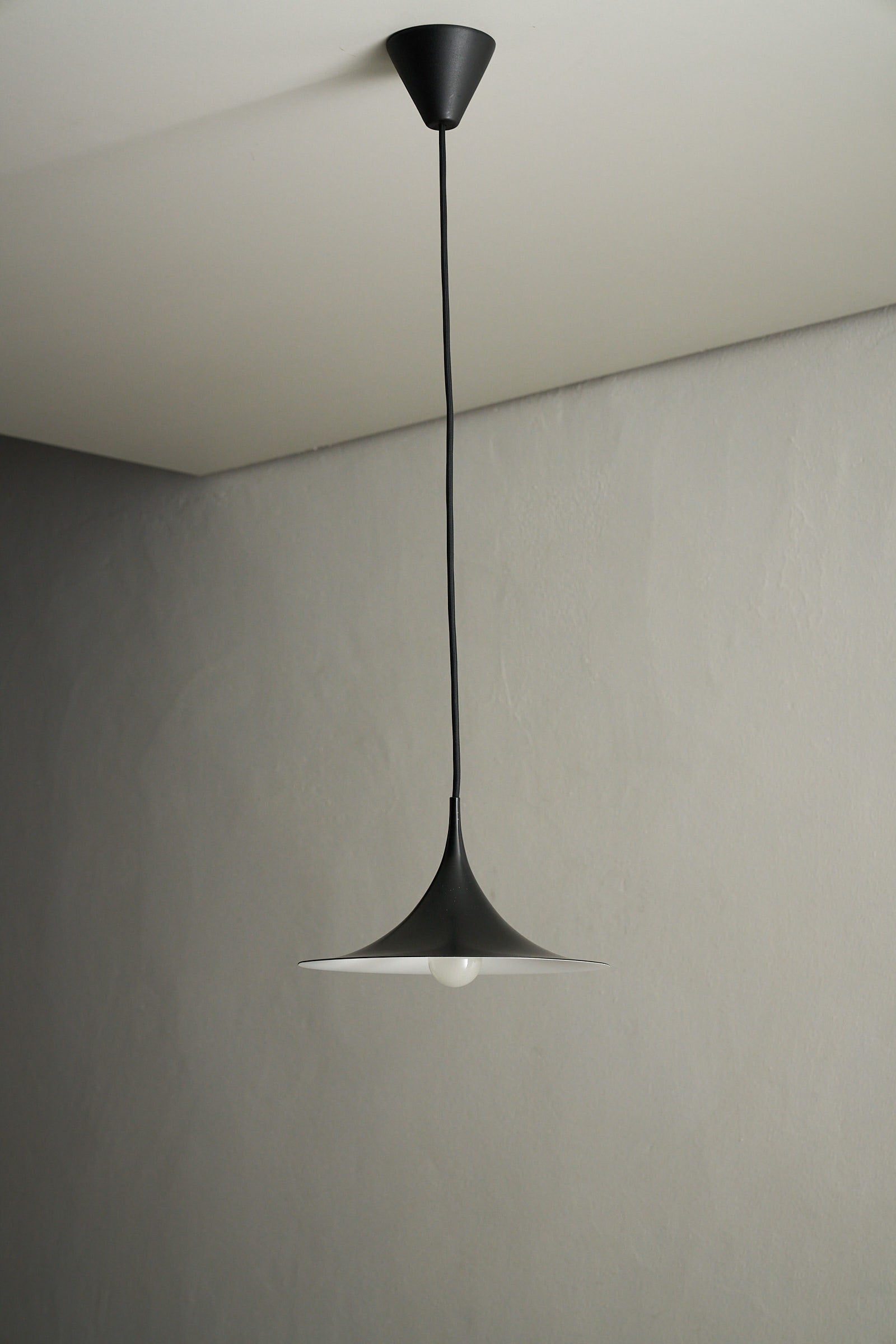 Small Fog & Mørup Black Semi Pendant Lamp hanging from the ceiling, showcasing its elegant design and light effect.