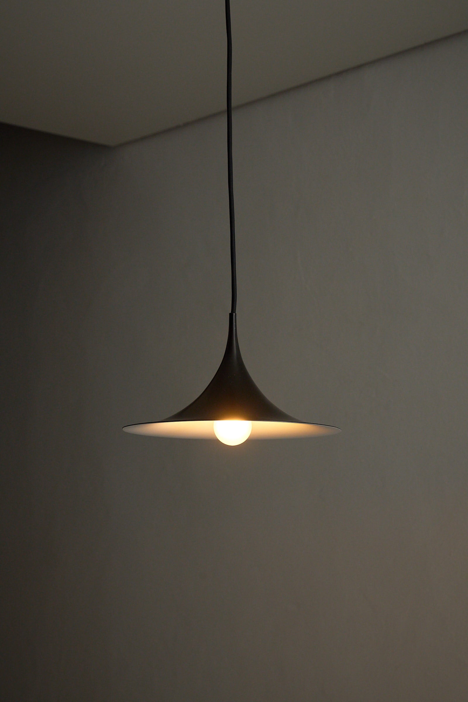 Small Fog & Mørup Black Semi Pendant Lamp hanging in a modern setting, showcasing its elegant design and optimal light effect.