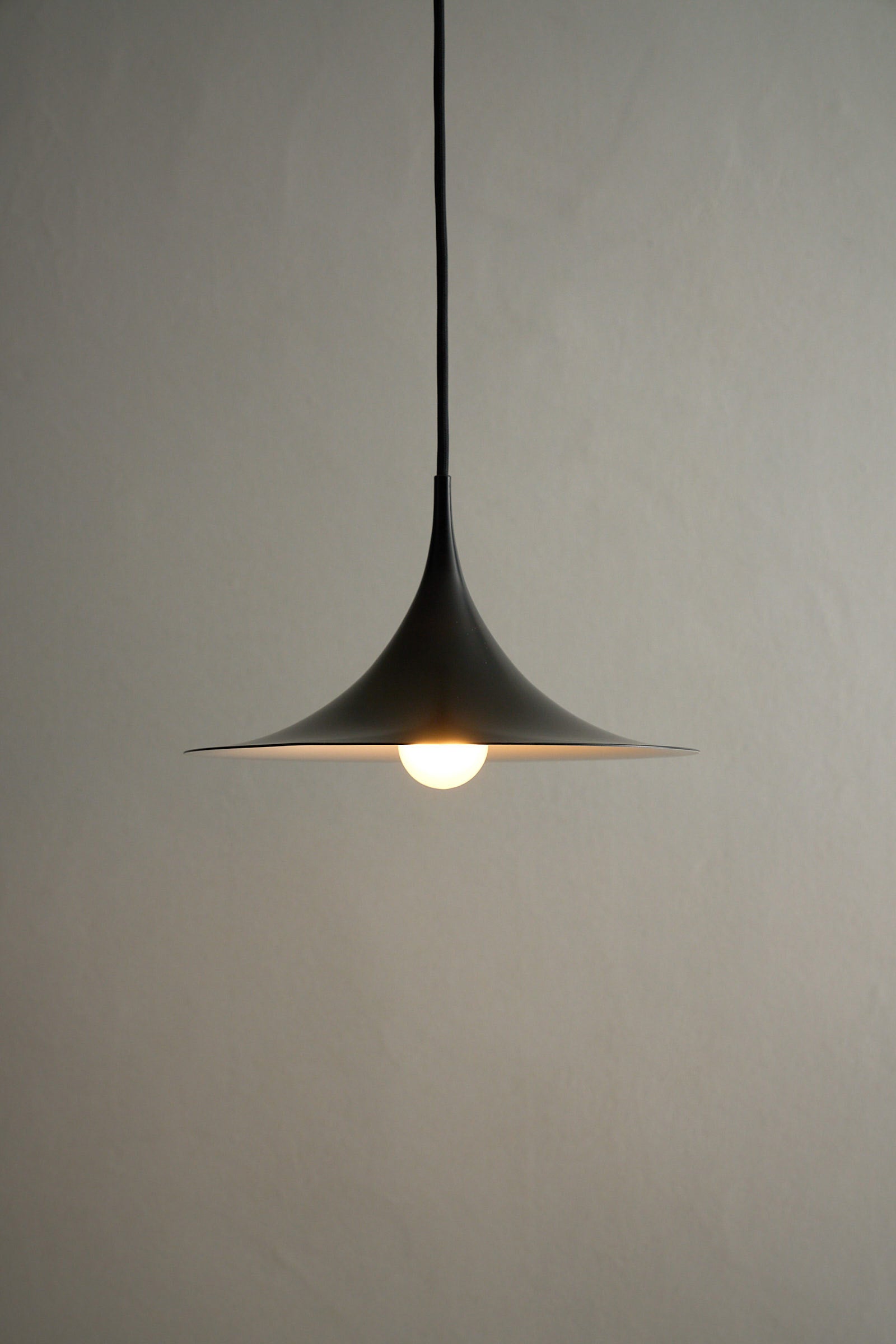 Small Fog & Mørup Black Semi Pendant Lamp hanging elegantly in a minimalistic setting with a warm glow.