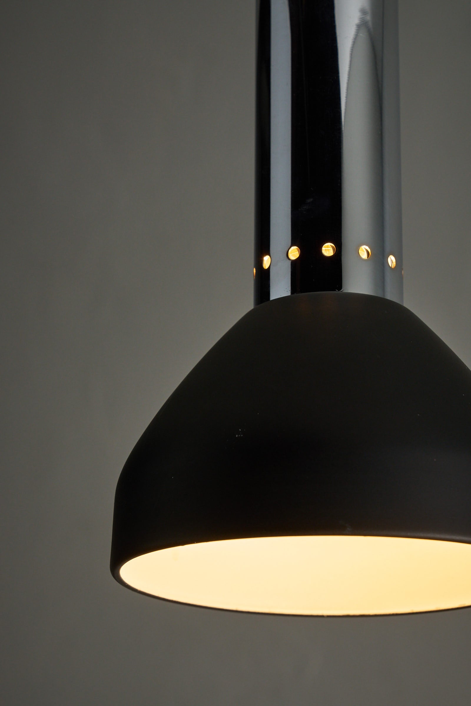 Chrome and Black Pendant Lamp with Perforated Detail featuring sleek lines and warm downlight.
