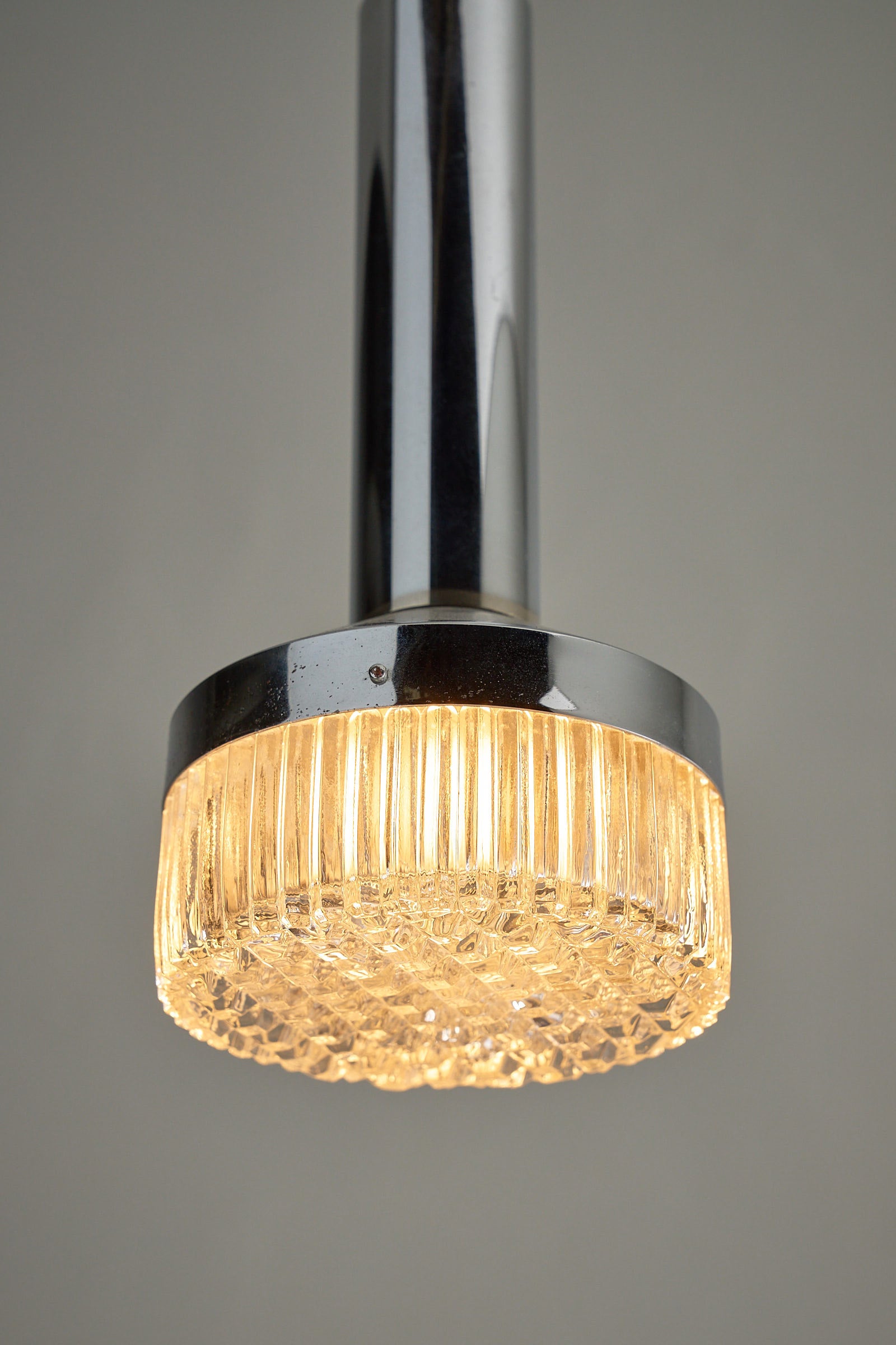 Chrome Pendant Lamp With Textured Glass Diffuser - Mid-Century Modern ceiling fixture with illuminated glass.