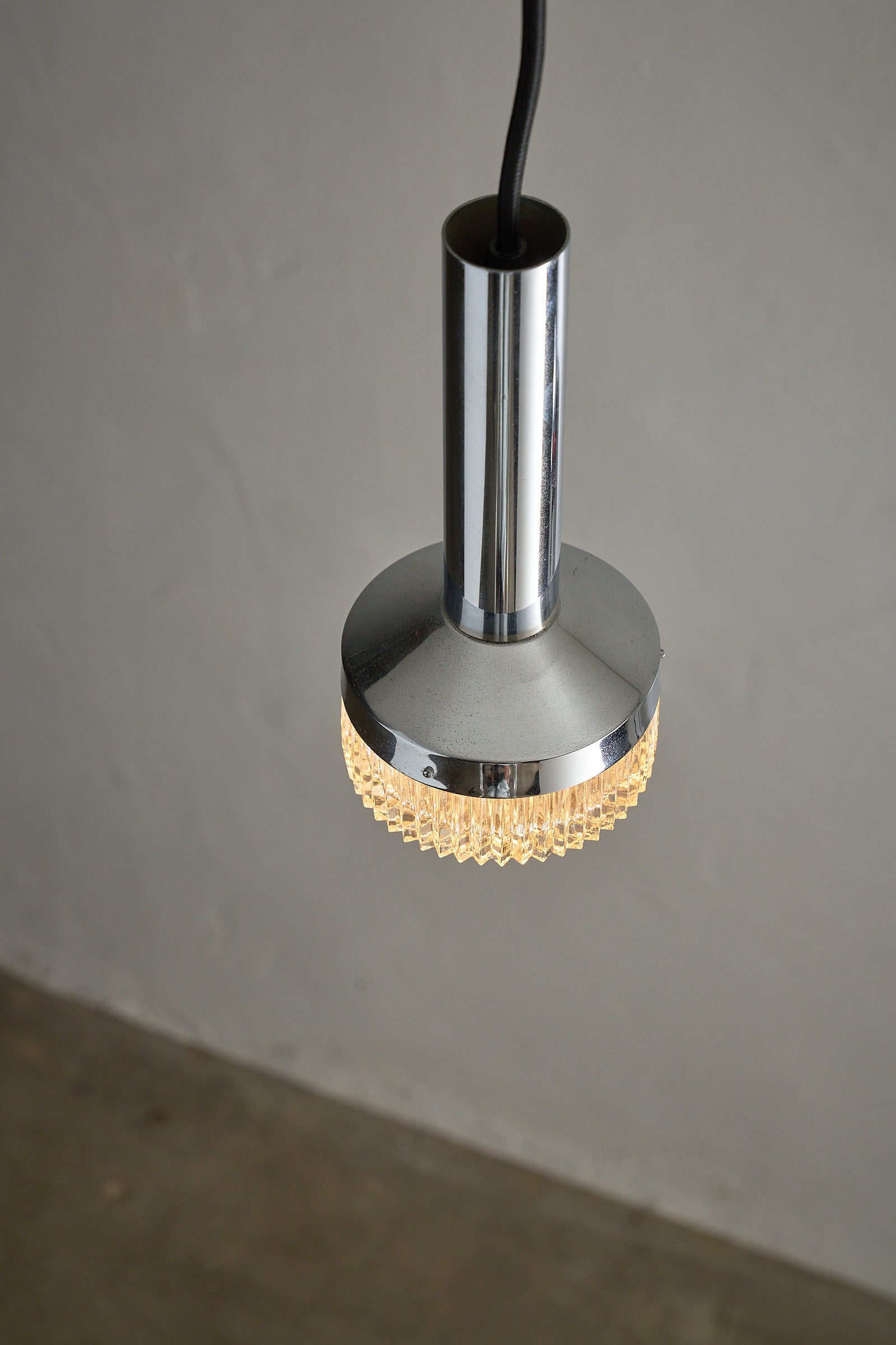 Chrome Pendant Lamp With Textured Glass Diffuser hanging from a ceiling, showcasing its polished chrome and textured glass design.