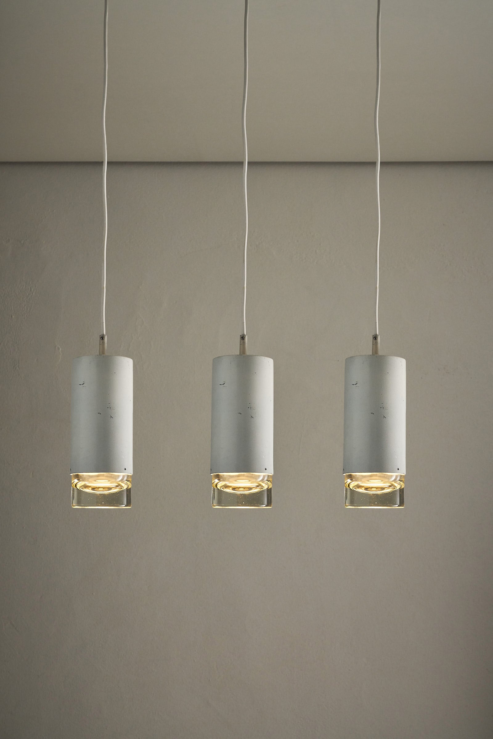 RAAK Amsterdam White Cylinder and Solid Glass Pendant Light trio hanging from ceiling