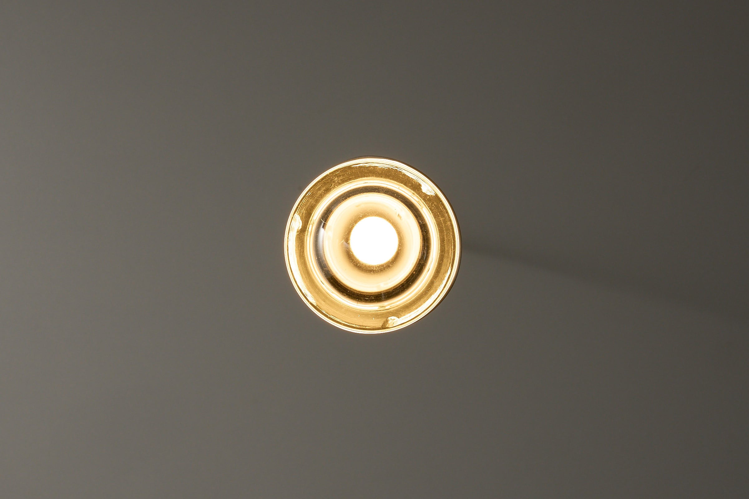RAAK Amsterdam White Cylinder and Solid Glass Pendant Light viewed from below, showcasing the clean metal design and bright light.