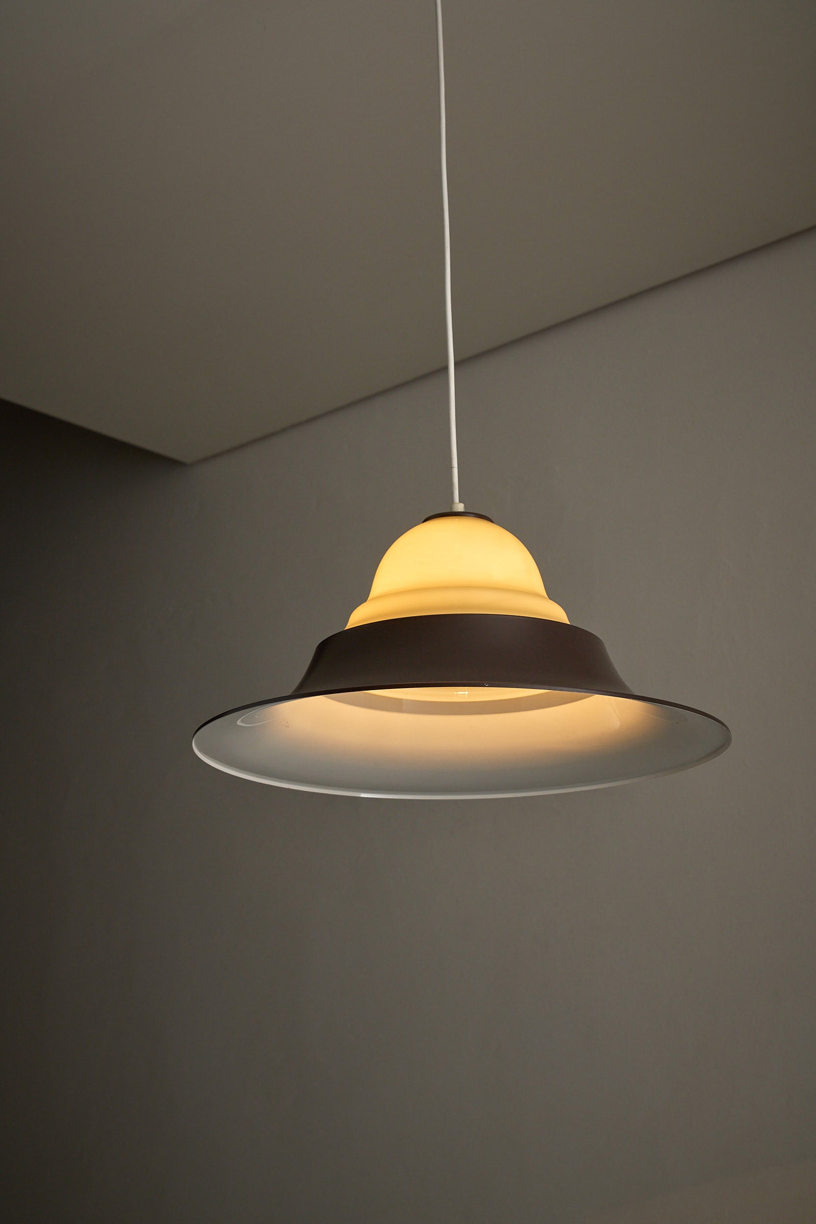 Mid-Century Modern Brown and Opaline Glass Layered Pendant hanging in a modern interior.