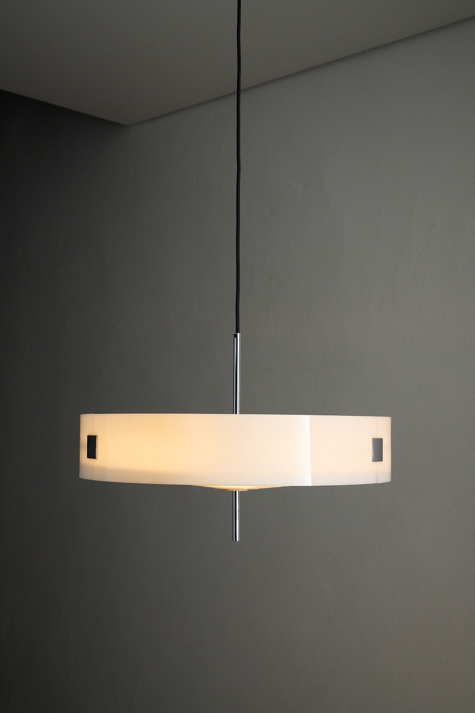 Cosack White Plexiglass Disc Pendant with Internal Grid hanging from the ceiling, showcasing its modern design and chrome fixings.