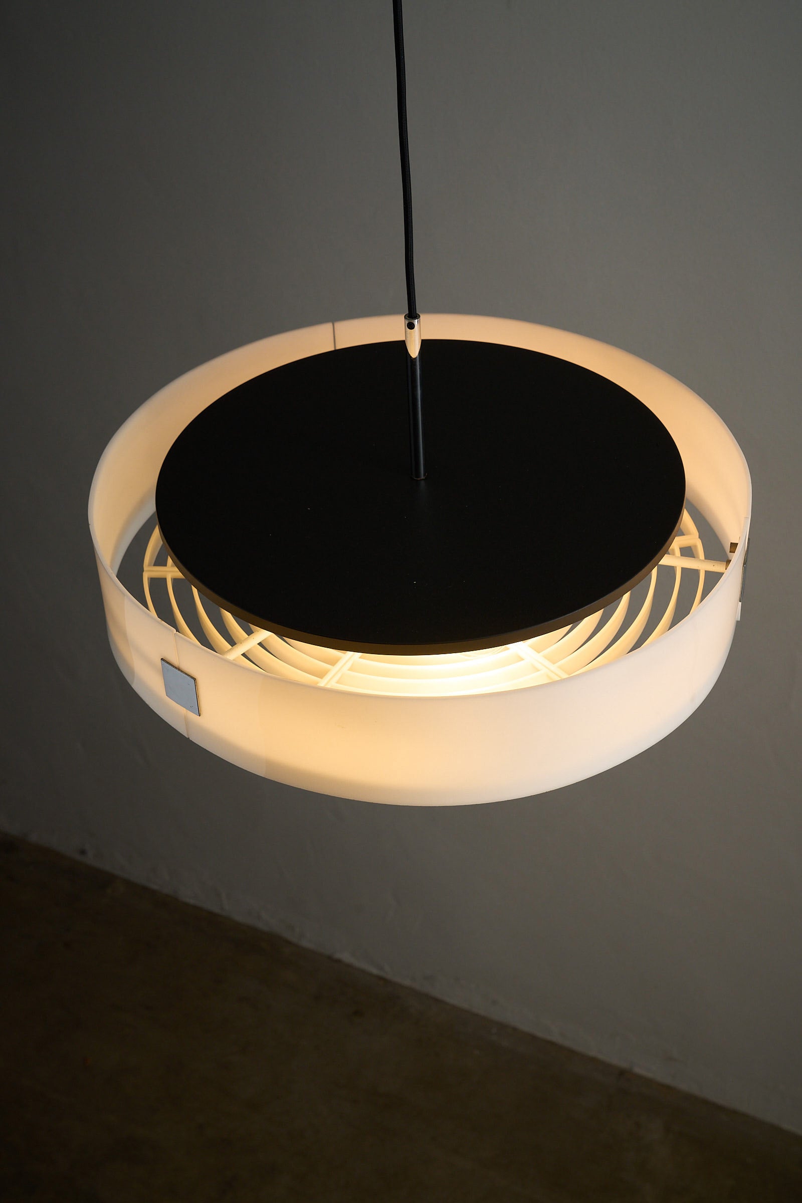 Cosack White Plexiglass Disc Pendant with Internal Grid hanging from a black ceiling, showcasing its modern design.