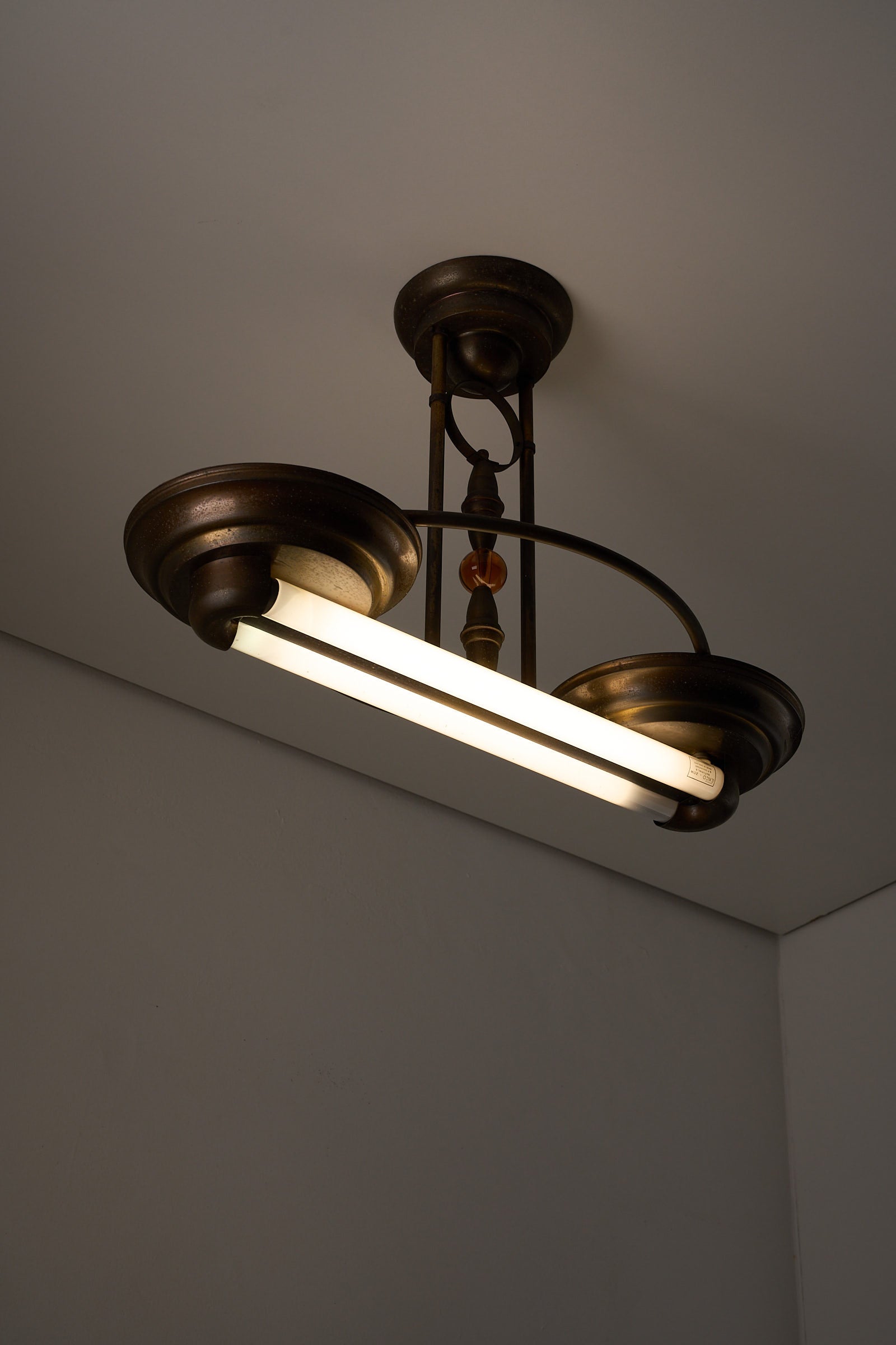 Antique Art Deco Double Fluorescent Ceiling Fixture in Patinated Bronze hanging from ceiling with amber accents.