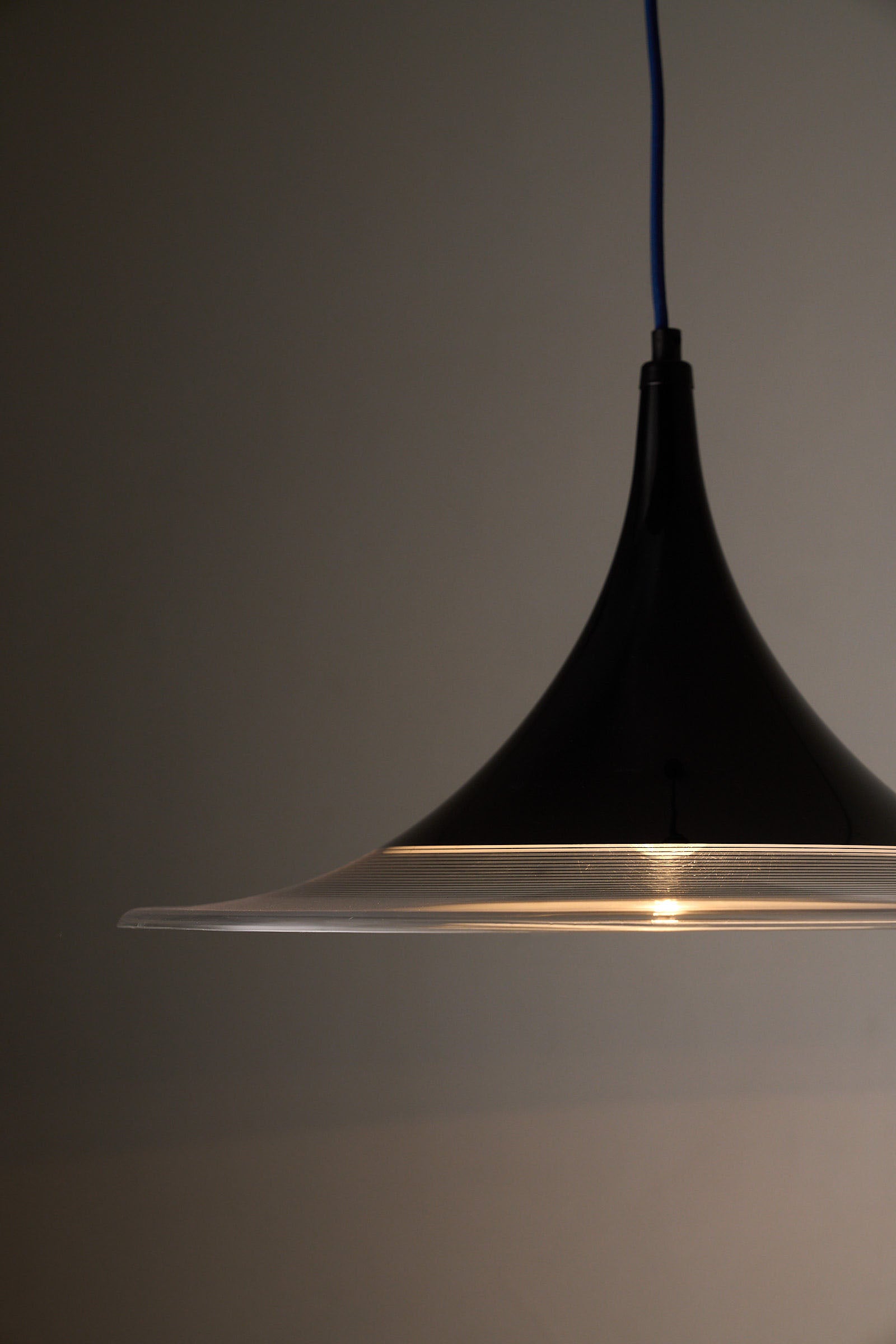 Black and Clear Acrylic Pendant lamp showcasing a concave conical silhouette and strong downward-focused light.