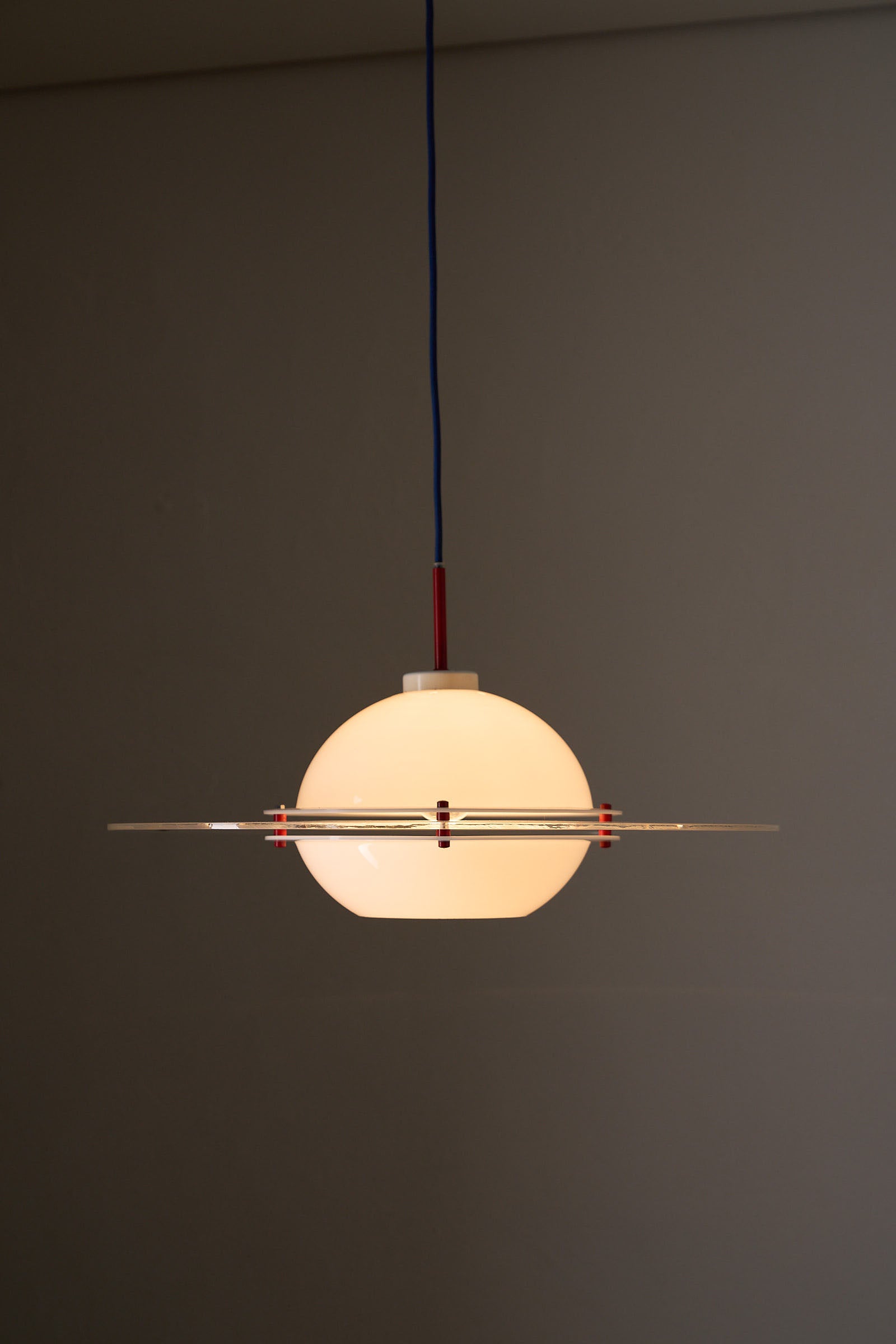 Space Age 'Saturn' Plexiglass Pendant Lamp with Red Details suspended against a grey wall.