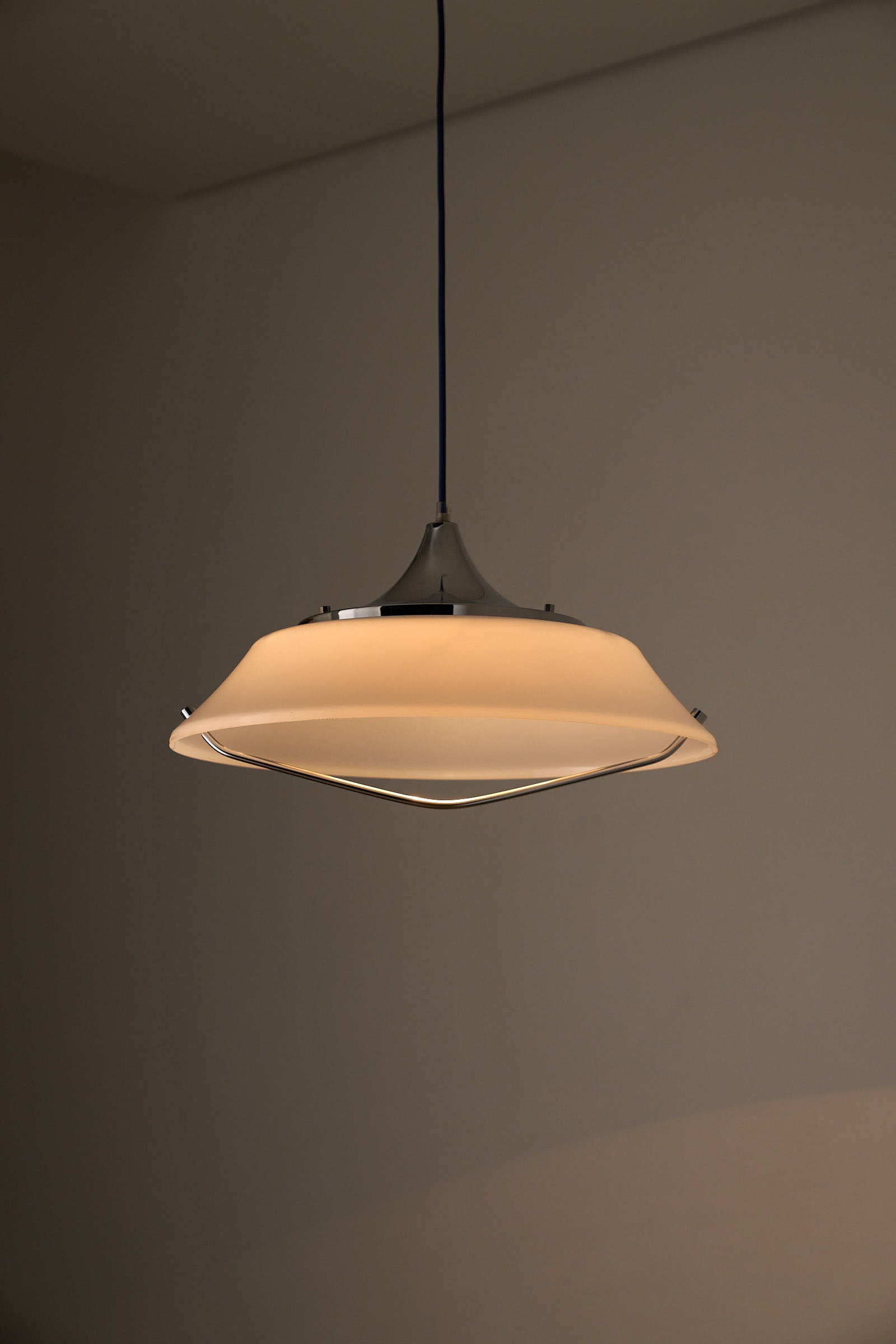 Mid-Century Modern White Acrylic Dish Pendant with Chrome Yoke hanging lamp providing soft ambient lighting.