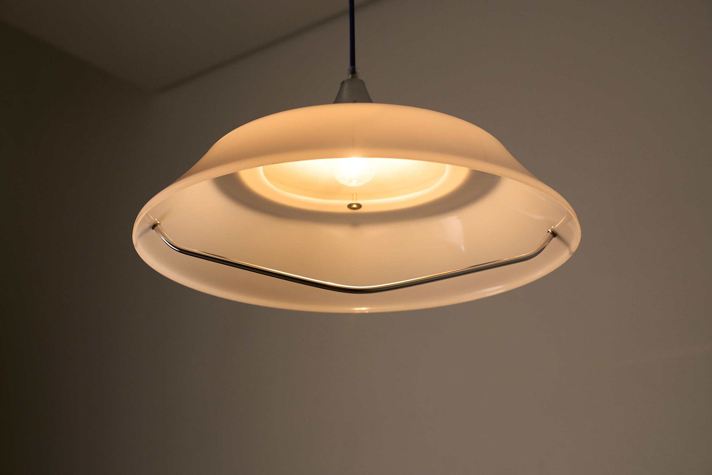 Mid-Century Modern White Acrylic Dish Pendant with Chrome Yoke hanging lamp illuminates softly.